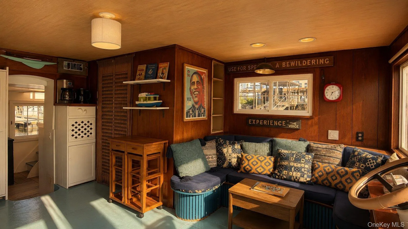 Warm wood paneling throughout, presenting a built-in corner sofa, multiple windows, recessed lighting, and a drum-style ceiling fixture Warm wood paneling throughout, presenting a built-in corner sofa, multiple windows, recessed lighting, and a drum-style ceiling fixture