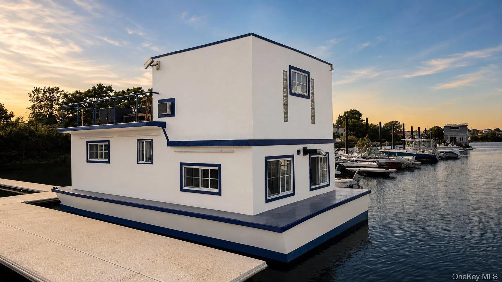 Two-story houseboat featuring white exterior siding with blue trim and black railings Two-story houseboat featuring white exterior siding with blue trim and black railings