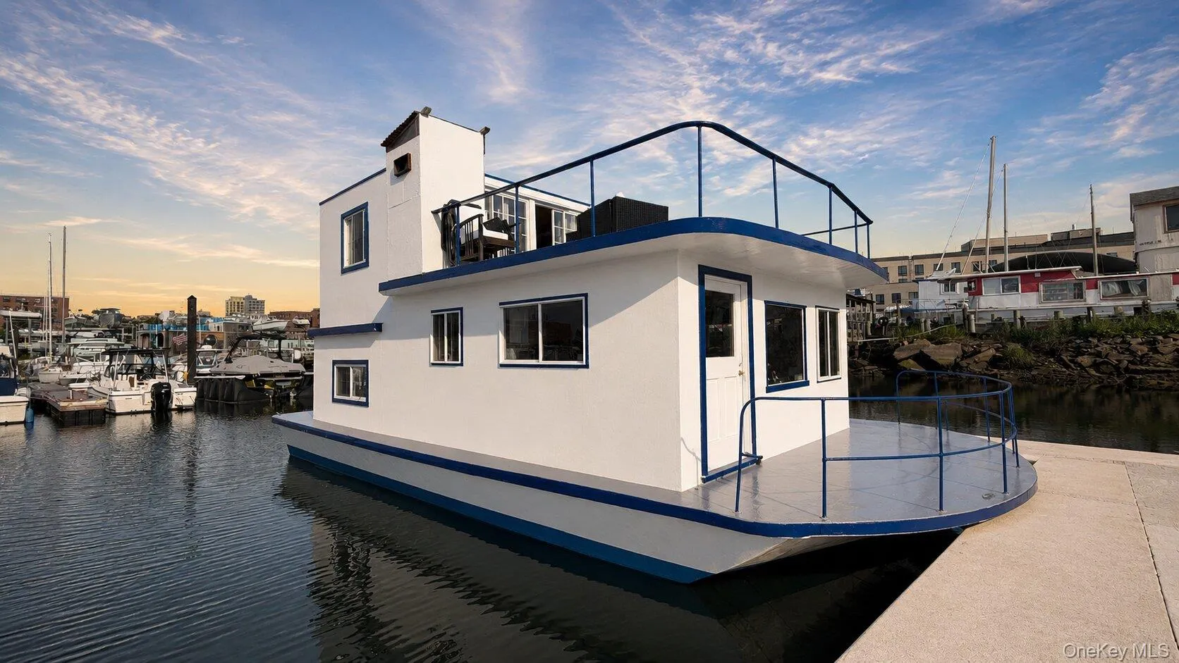 Two-story houseboat featuring white exterior siding with blue trim and black railings Two-story houseboat featuring white exterior siding with blue trim and black railings