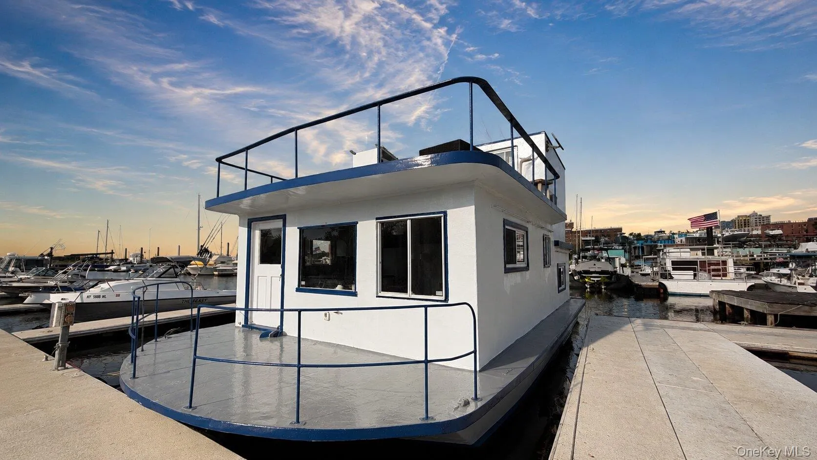 Two-story houseboat featuring white exterior siding with blue trim and black railings Two-story houseboat featuring white exterior siding with blue trim and black railings