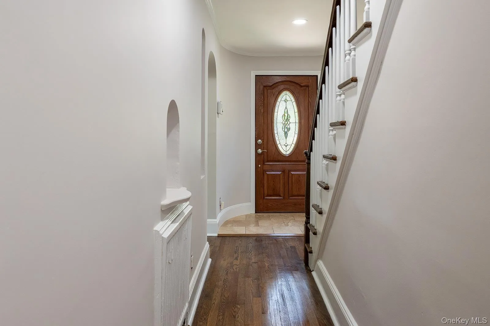 Hardwood flooring entry with a wooden front door featuring an oval leaded glass insert Hardwood flooring entry with a wooden front door featuring an oval leaded glass insert