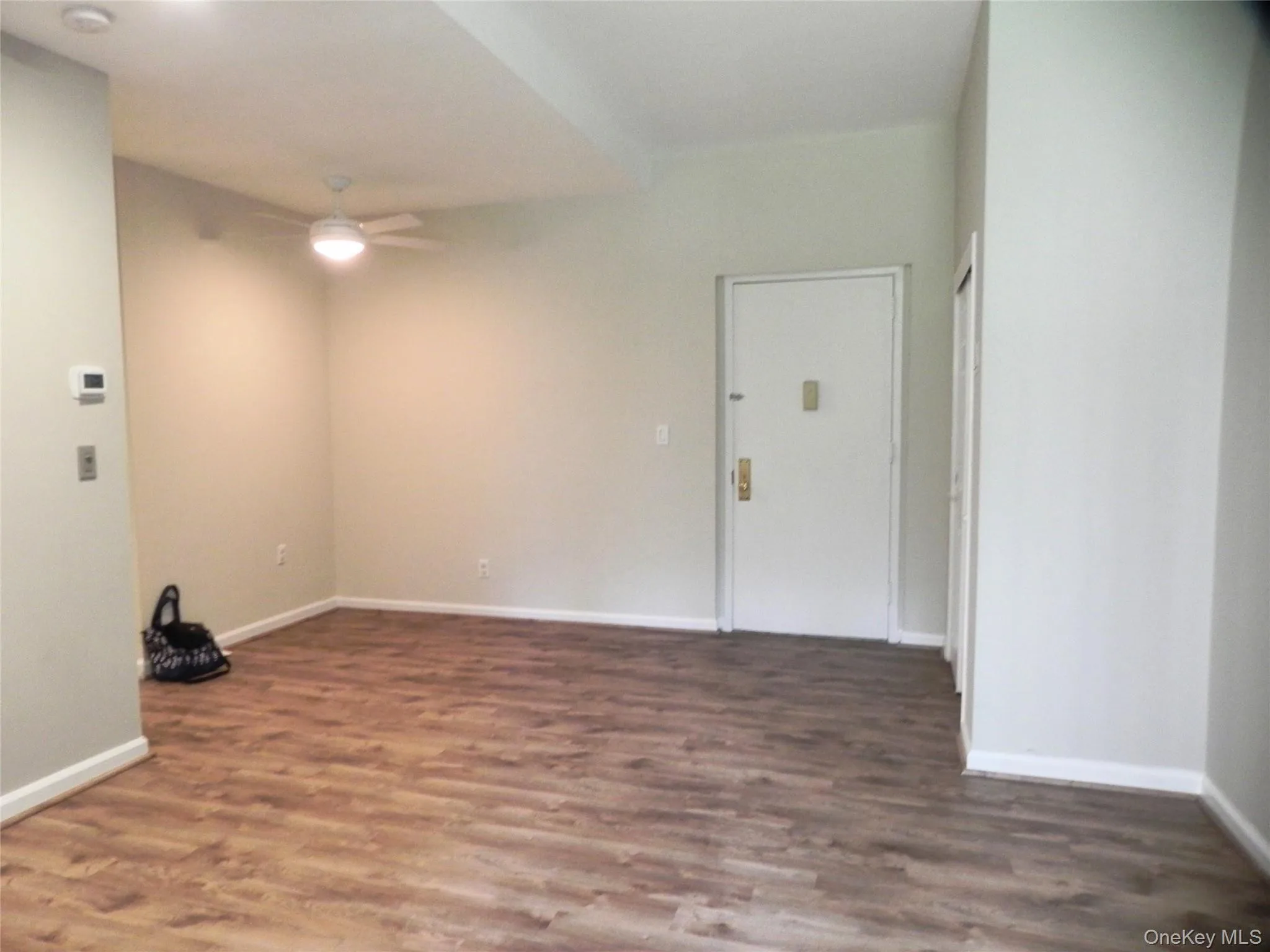 Empty room with ceiling fan, wood finished floors, and a smoke detector Empty room with ceiling fan, wood finished floors, and a smoke detector