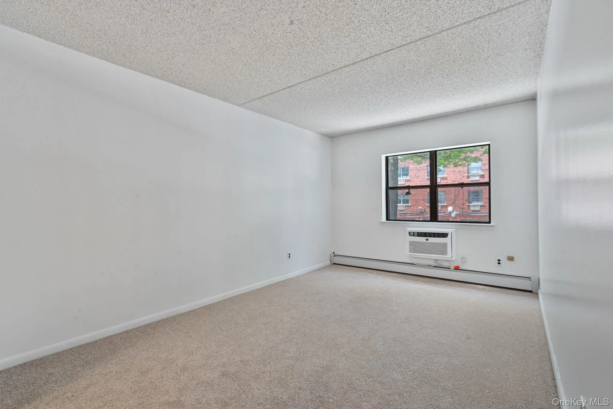 Carpeted room featuring a window with a window-mounted air conditioning unit Carpeted room featuring a window with a window-mounted air conditioning unit