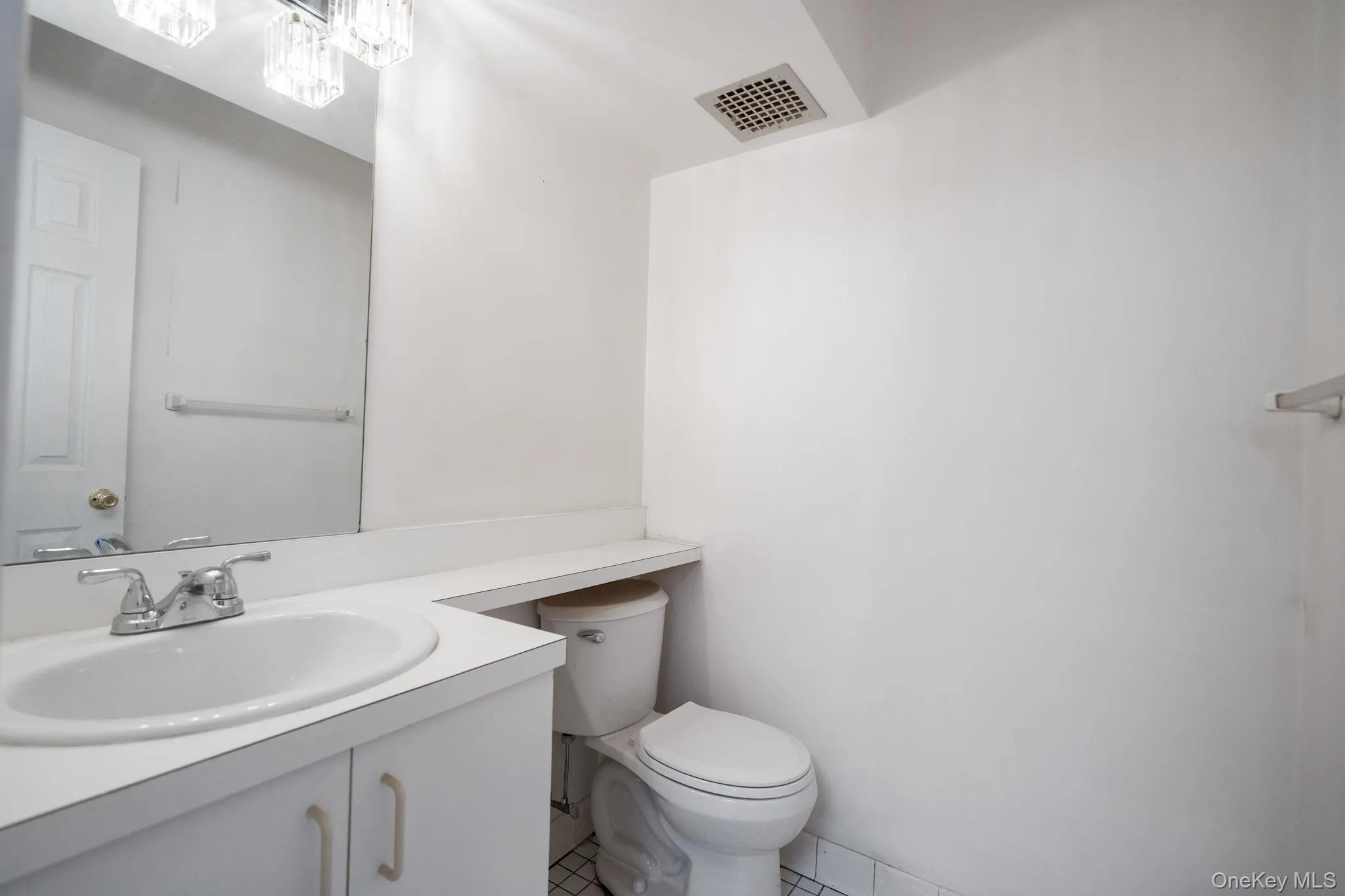 Bathroom featuring a vanity with an integrated sink, chrome faucet, and mirrored wall Bathroom featuring a vanity with an integrated sink, chrome faucet, and mirrored wall