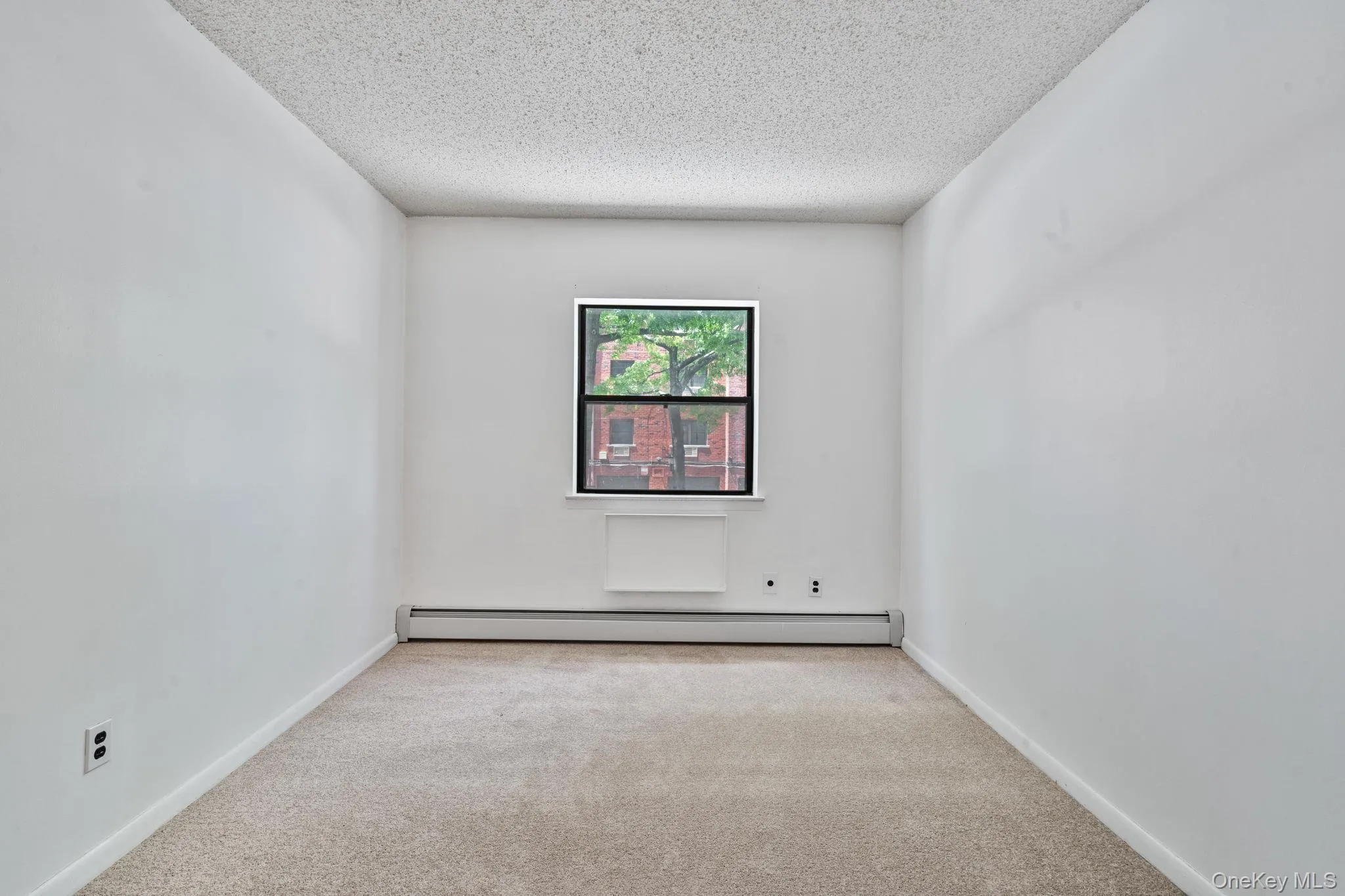 Neutral wall paint with textured ceiling, light-colored carpet flooring, and a single window offering exterior views Neutral wall paint with textured ceiling, light-colored carpet flooring, and a single window offering exterior views