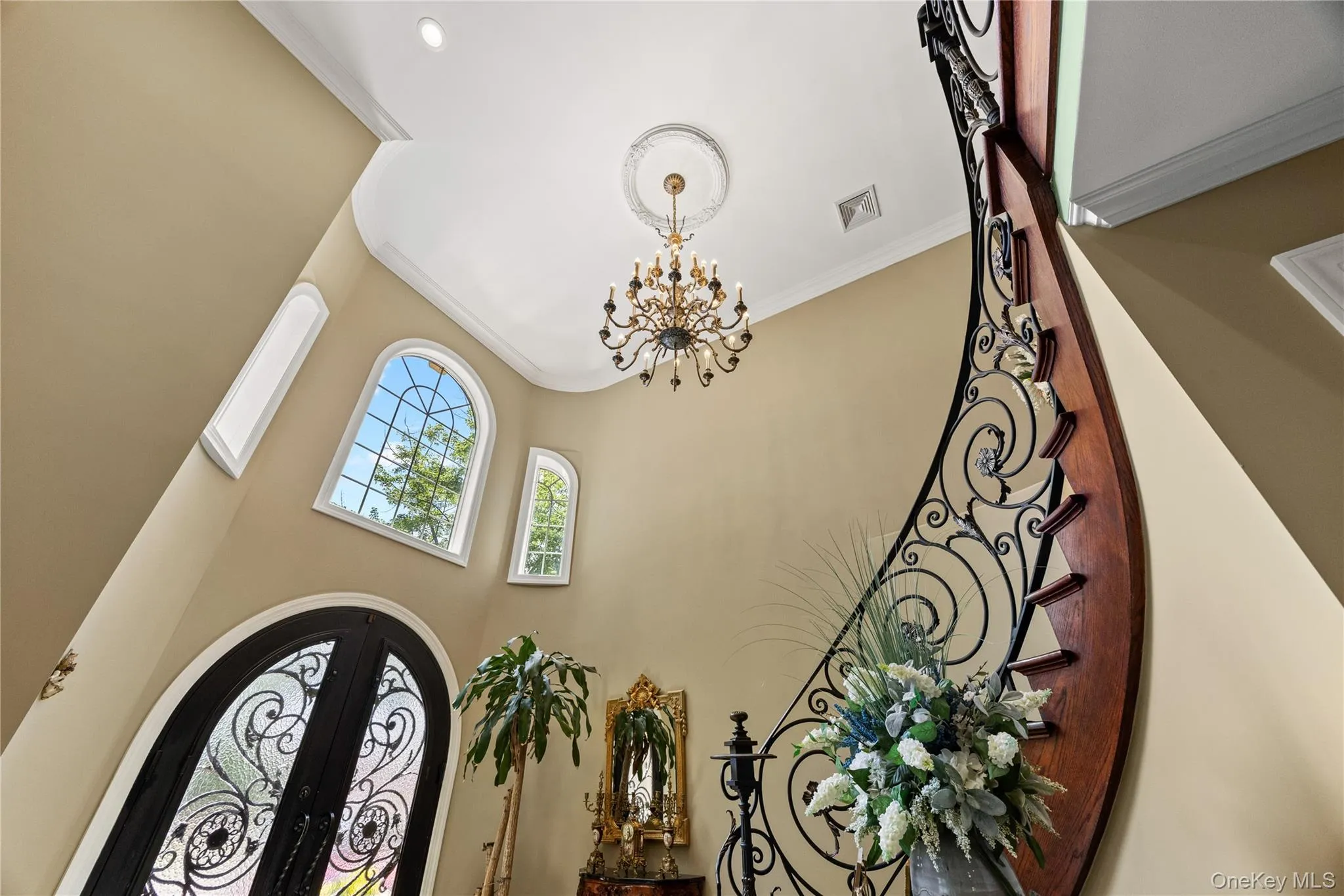 Grand entry featuring a sweeping curved staircase with wrought iron balusters and hardwood treads Grand entry featuring a sweeping curved staircase with wrought iron balusters and hardwood treads