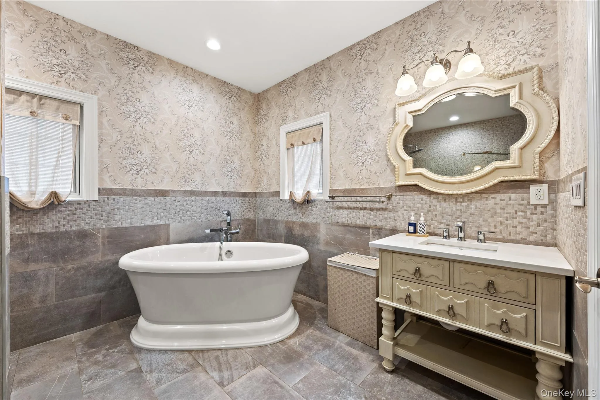 Freestanding soaking tub complemented by a distressed vanity with a white countertop Freestanding soaking tub complemented by a distressed vanity with a white countertop