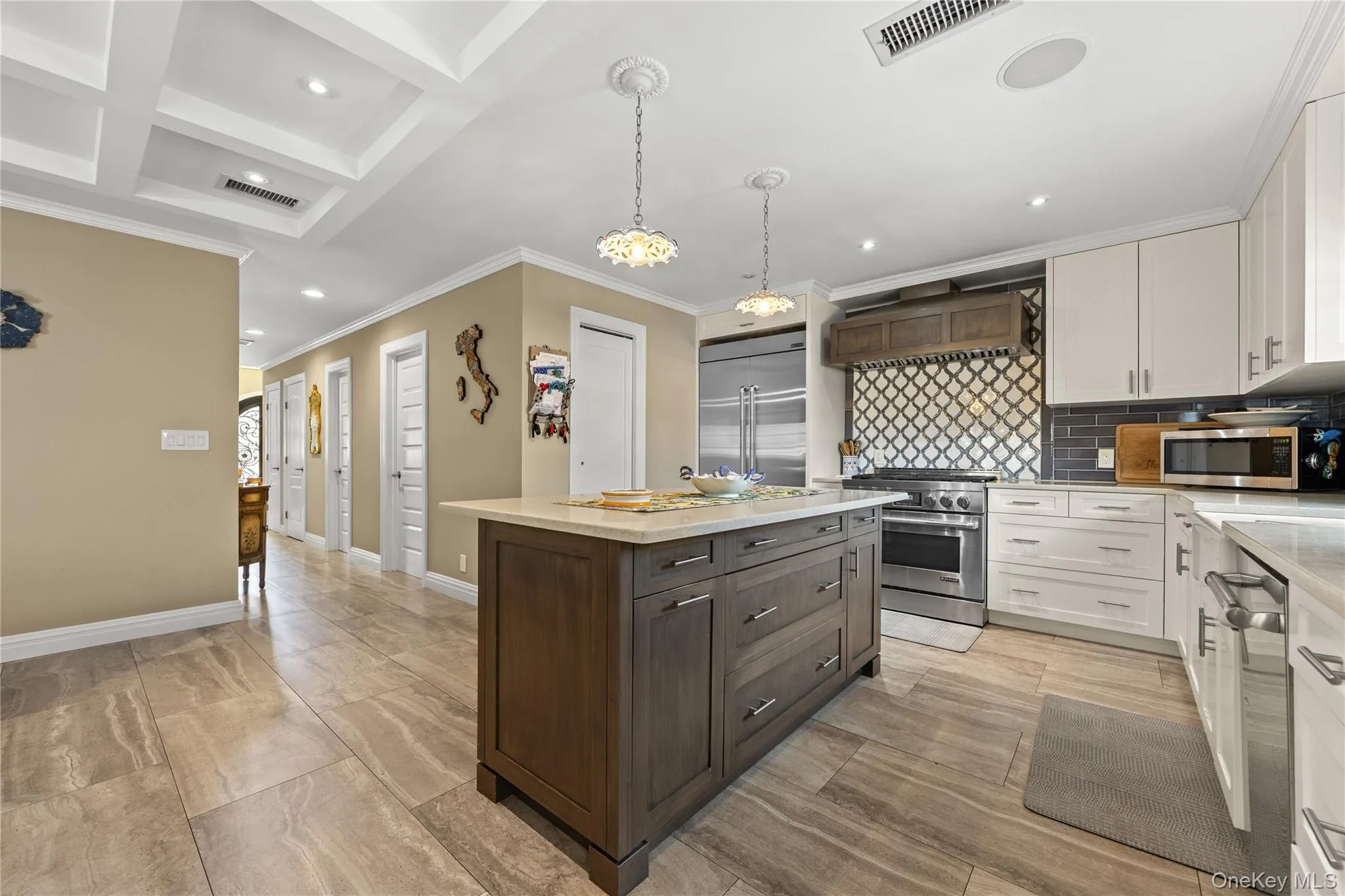 Gourmet kitchen featuring a central island with storage, stainless steel appliances, decorative tile backsplash, white cabinetry, and recessed lighting Gourmet kitchen featuring a central island with storage, stainless steel appliances, decorative tile backsplash, white cabinetry, and recessed lighting