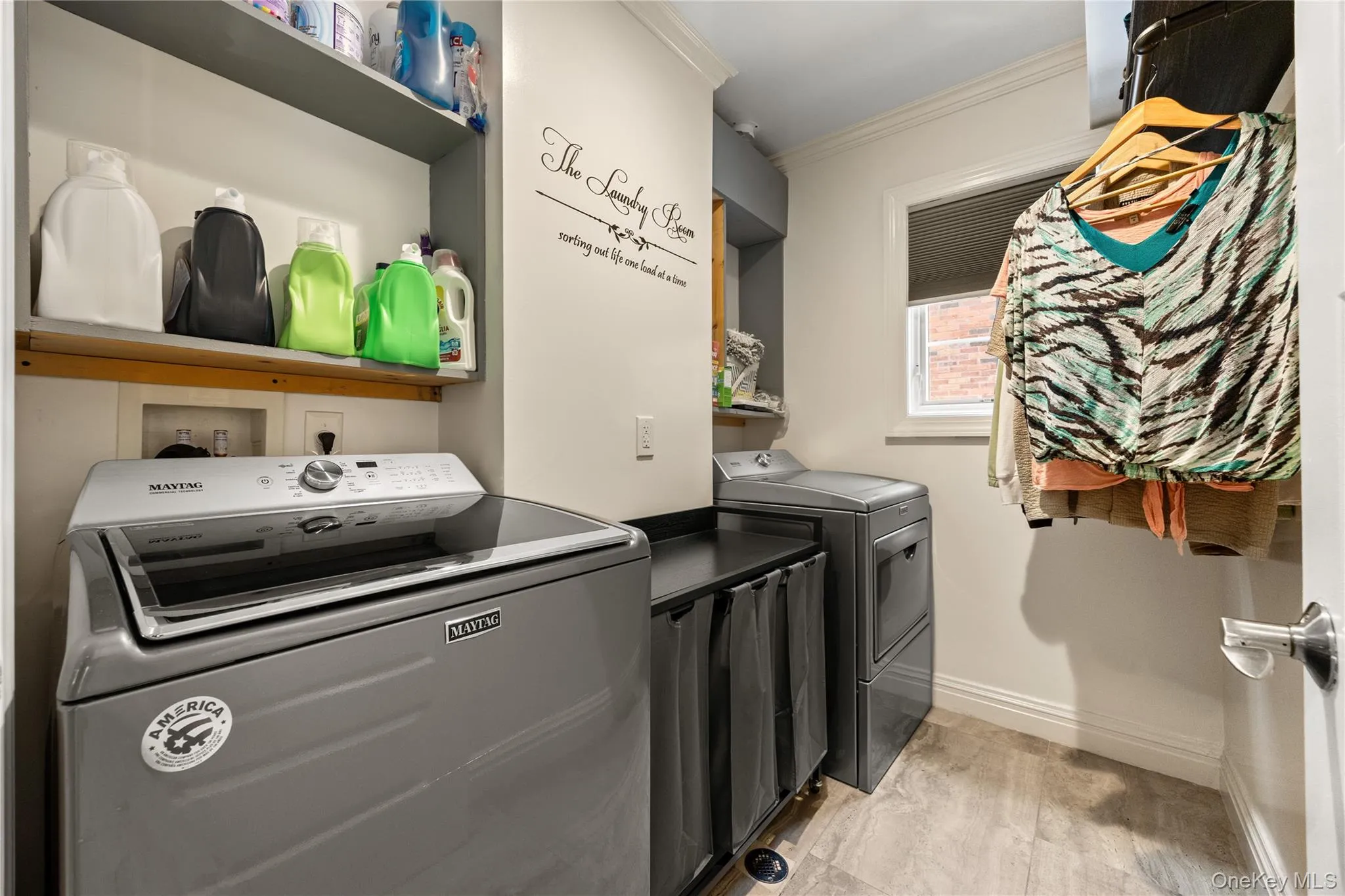 Dedicated laundry area featuring a window, overhead shelving, and light-toned flooring Dedicated laundry area featuring a window, overhead shelving, and light-toned flooring