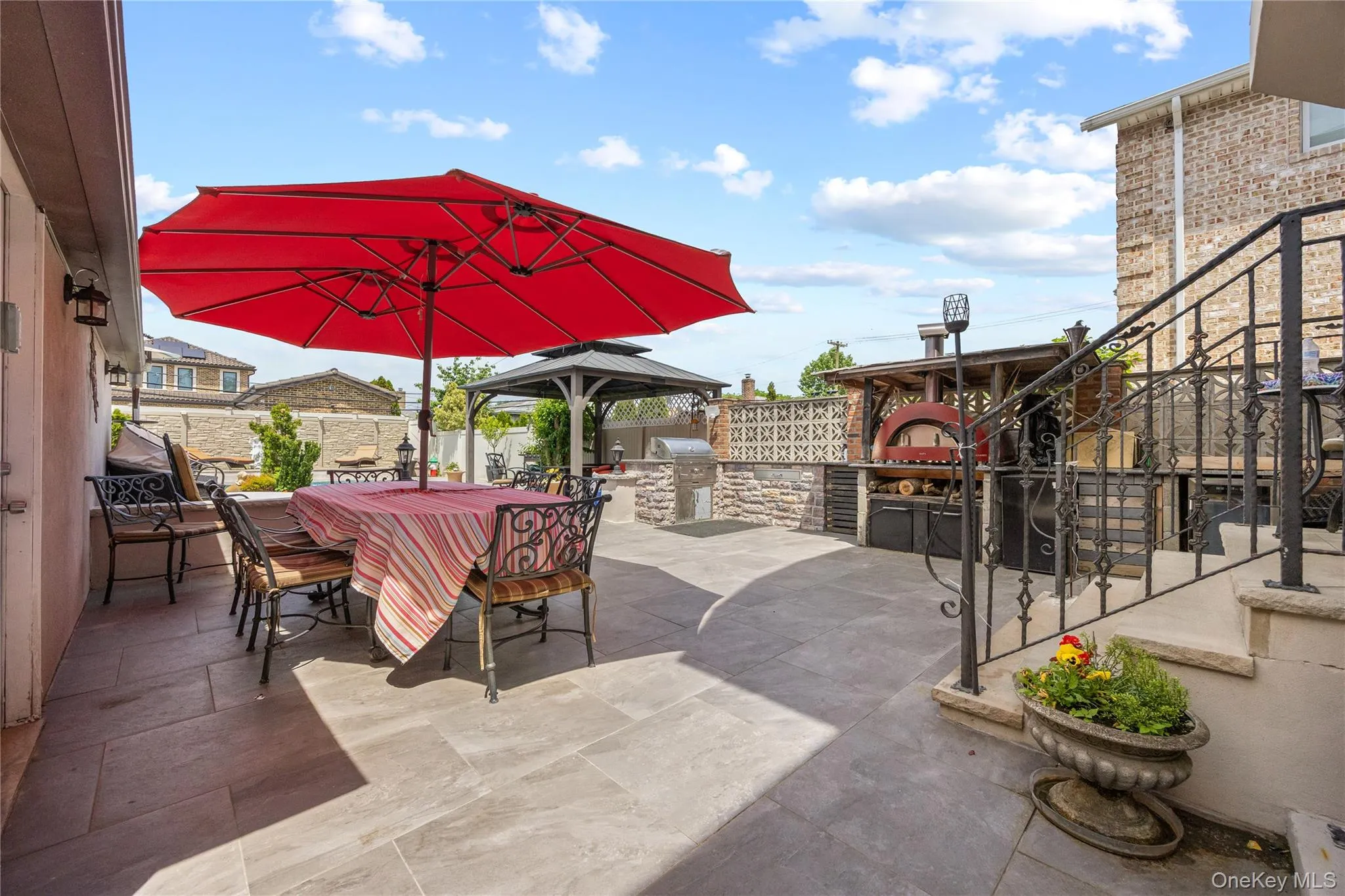 Expansive outdoor patio featuring large format tile flooring and a built-in outdoor kitchen with a pizza oven Expansive outdoor patio featuring large format tile flooring and a built-in outdoor kitchen with a pizza oven