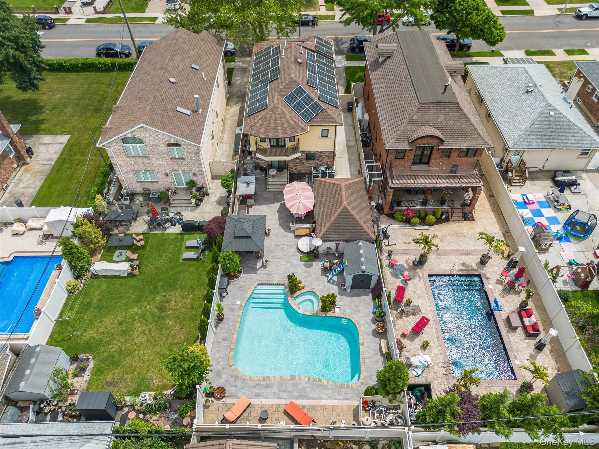 Expansive rear yard featuring a curved in-ground swimming pool with an integrated spa, complemented by a paver patio and a separate gazebo structure Expansive rear yard featuring a curved in-ground swimming pool with an integrated spa, complemented by a paver patio and a separate gazebo structure