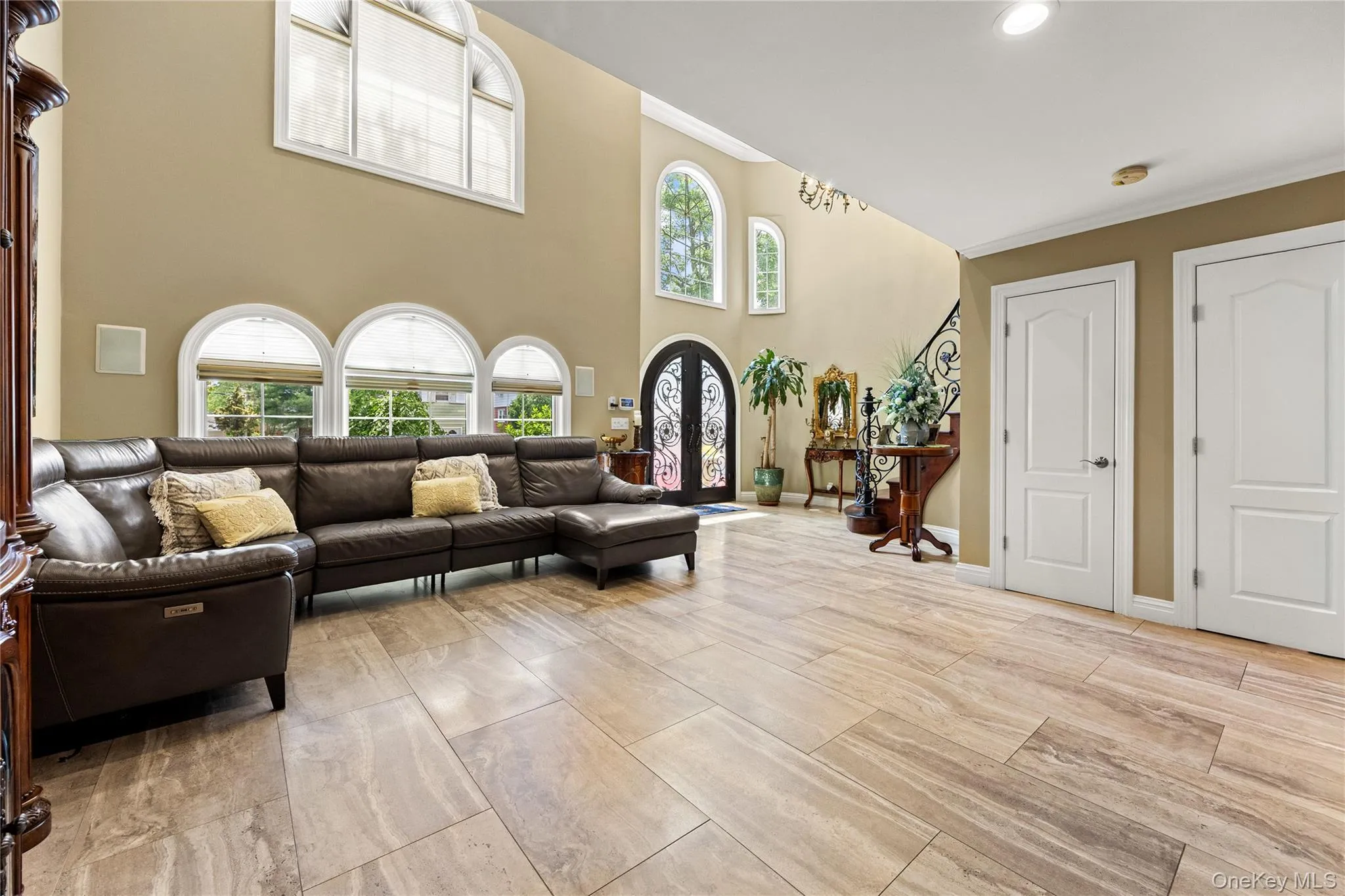 Two-story foyer featuring large format tile flooring, arched windows, and a decorative wrought iron staircase Two-story foyer featuring large format tile flooring, arched windows, and a decorative wrought iron staircase