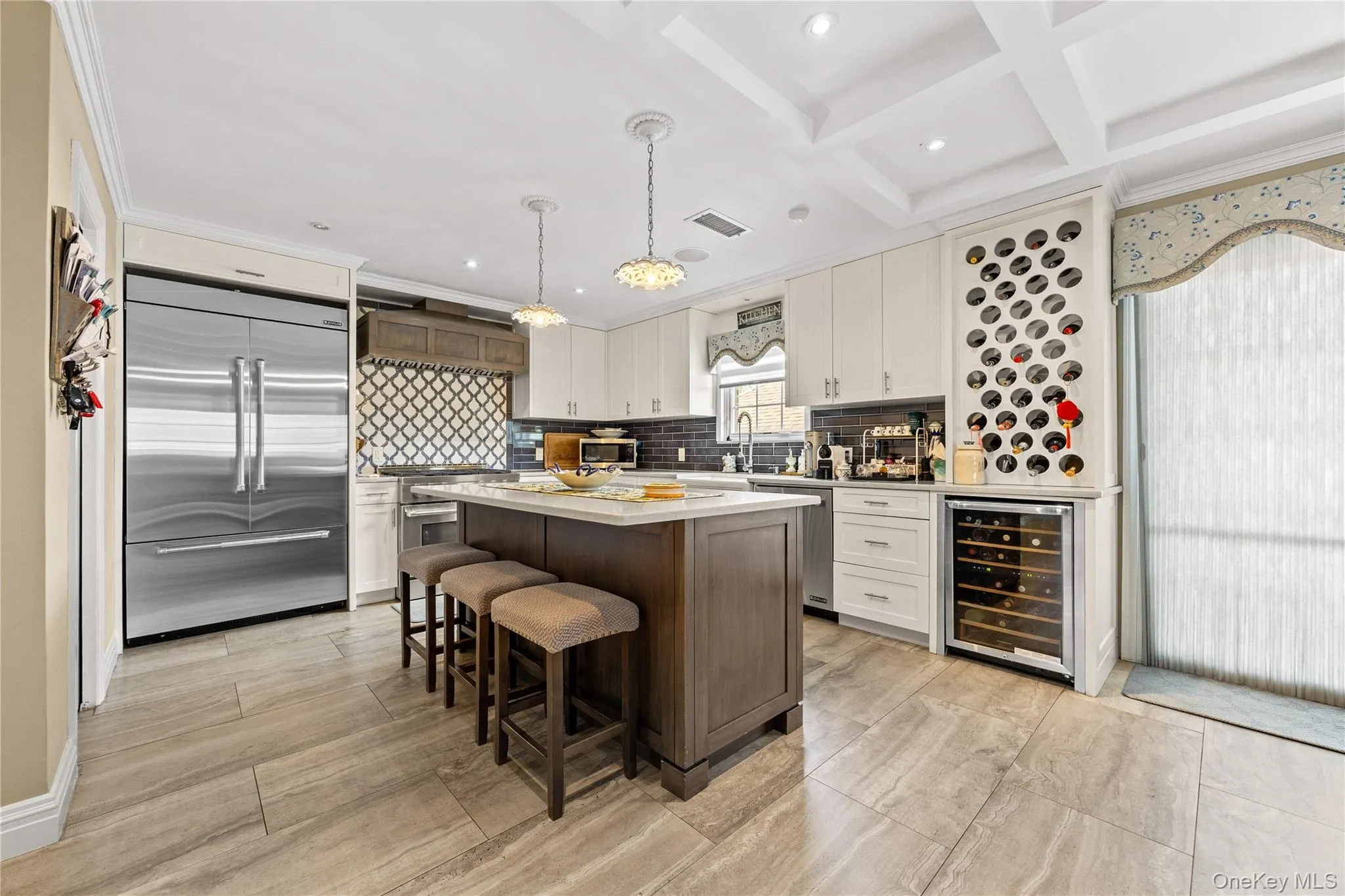 Gourmet kitchen featuring a wood-finish island with seating, stainless steel appliances, a built-in wine rack, and a beverage refrigerator Gourmet kitchen featuring a wood-finish island with seating, stainless steel appliances, a built-in wine rack, and a beverage refrigerator