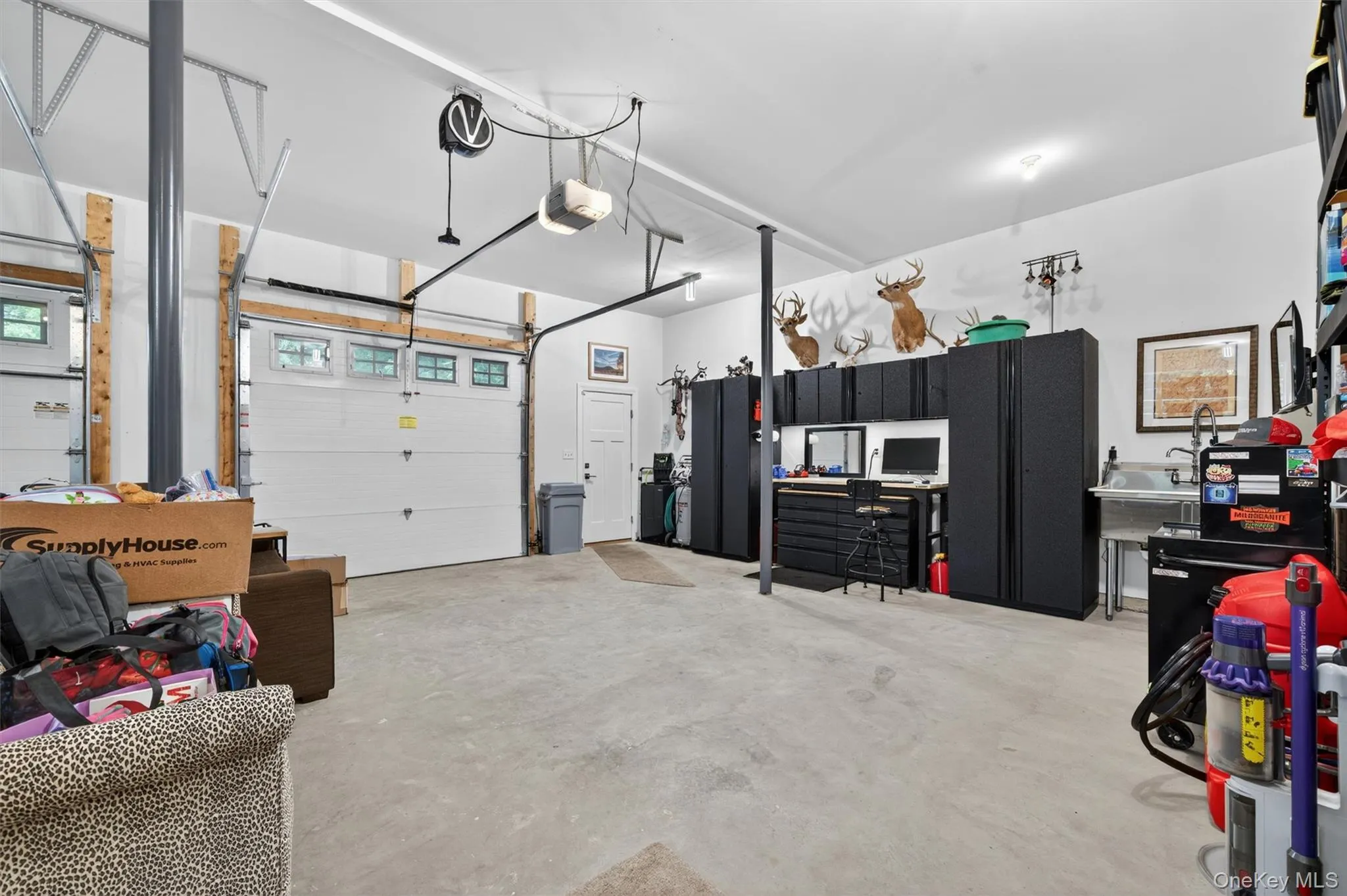 Spacious garage featuring two overhead doors with window accents, concrete flooring, and ample built-in storage cabinetry Spacious garage featuring two overhead doors with window accents, concrete flooring, and ample built-in storage cabinetry