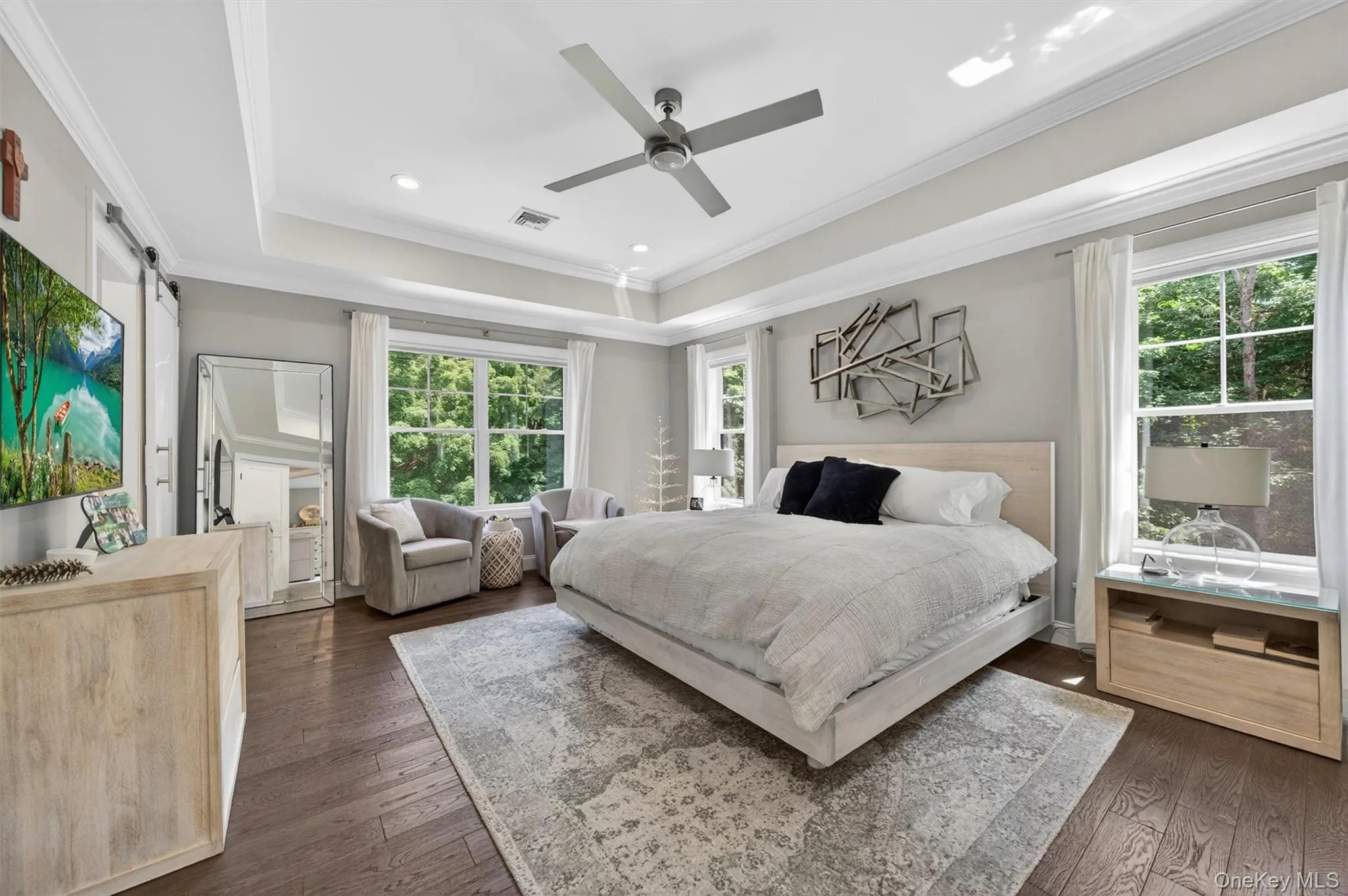 Spacious room featuring rich wood-finish flooring and a tray ceiling with crown molding Spacious room featuring rich wood-finish flooring and a tray ceiling with crown molding