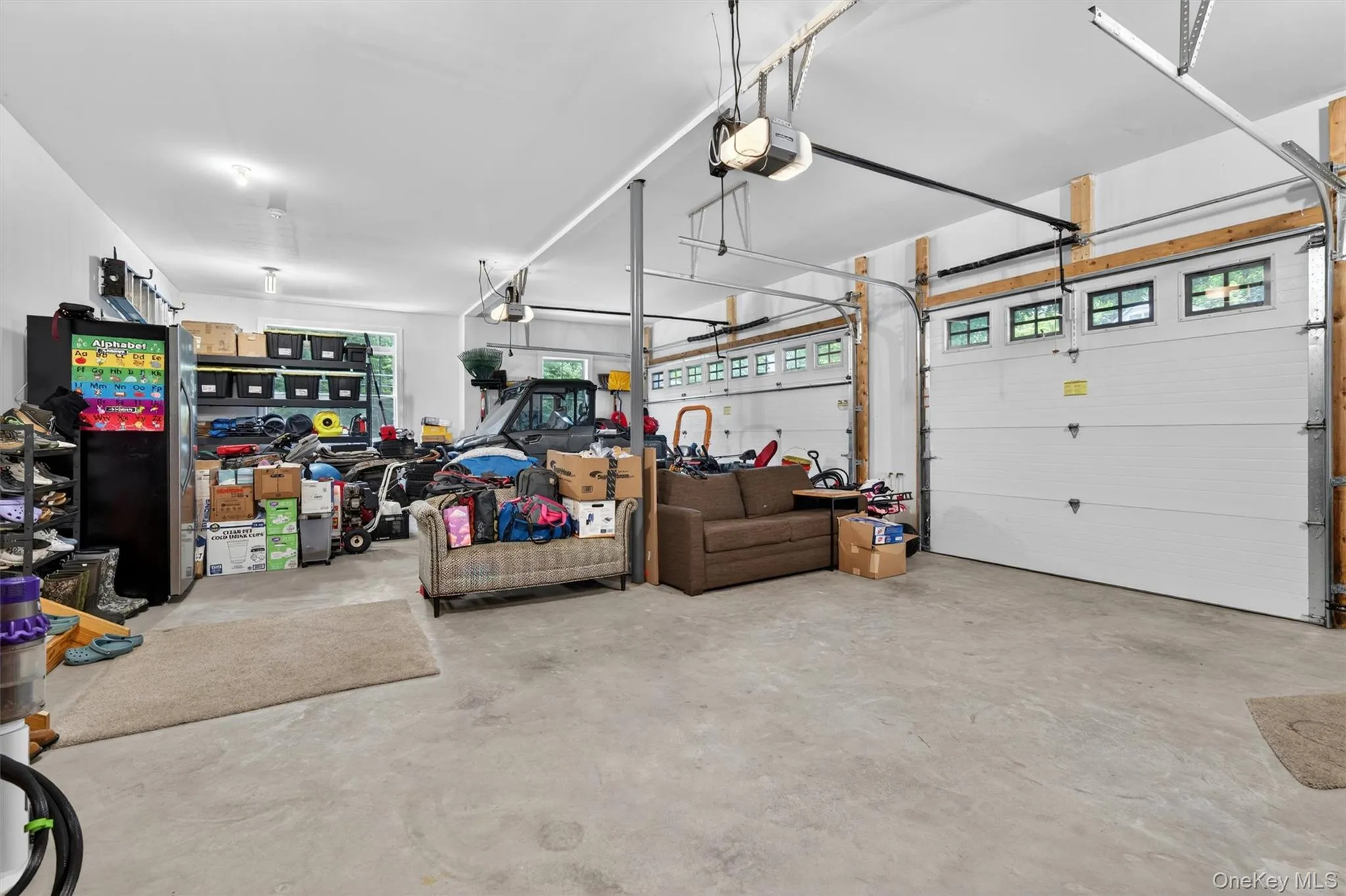 Spacious garage featuring concrete flooring and dual overhead doors with upper window inserts Spacious garage featuring concrete flooring and dual overhead doors with upper window inserts
