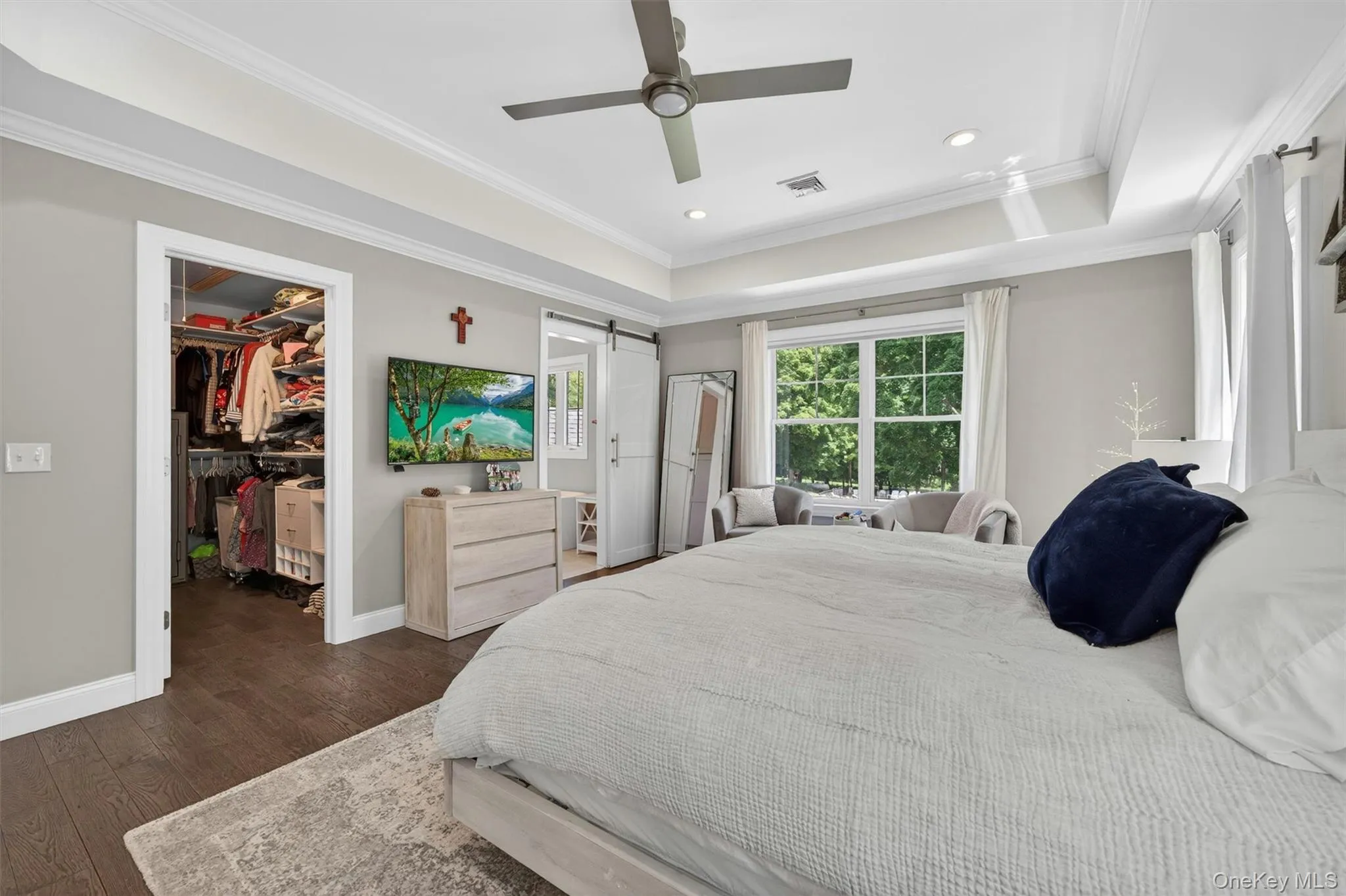 Bedroom featuring wood-finish flooring, recessed lighting, and a window overlooking greenery Bedroom featuring wood-finish flooring, recessed lighting, and a window overlooking greenery