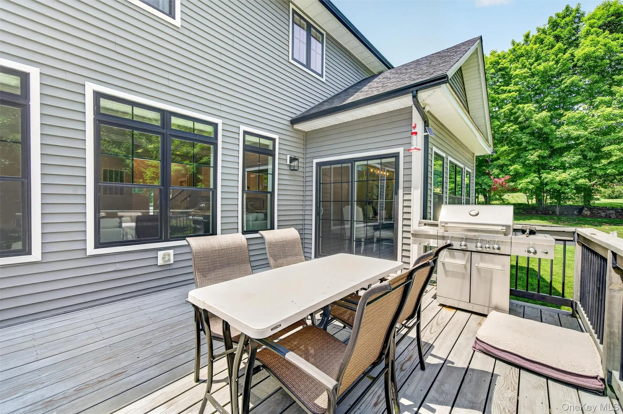 Spacious outdoor deck featuring light-toned wood-finish flooring, a stainless steel grill, and direct access to interior spaces through large sliding glass doors Spacious outdoor deck featuring light-toned wood-finish flooring, a stainless steel grill, and direct access to interior spaces through large sliding glass doors
