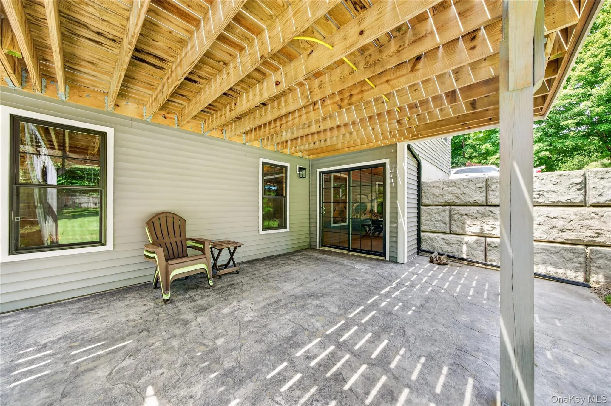 Covered patio with stamped concrete flooring and exposed wood beam ceiling Covered patio with stamped concrete flooring and exposed wood beam ceiling
