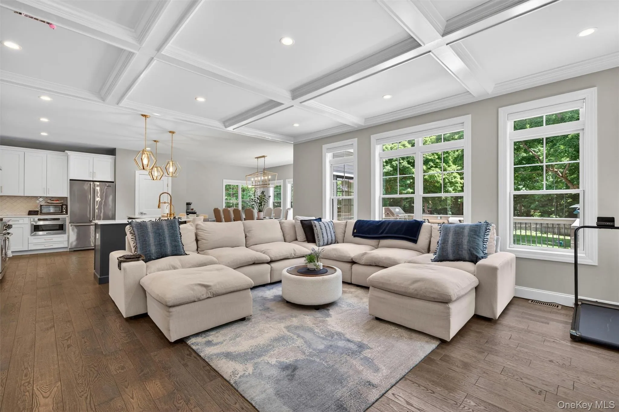 Spacious living area featuring coffered ceilings, recessed lighting, and large windows Spacious living area featuring coffered ceilings, recessed lighting, and large windows