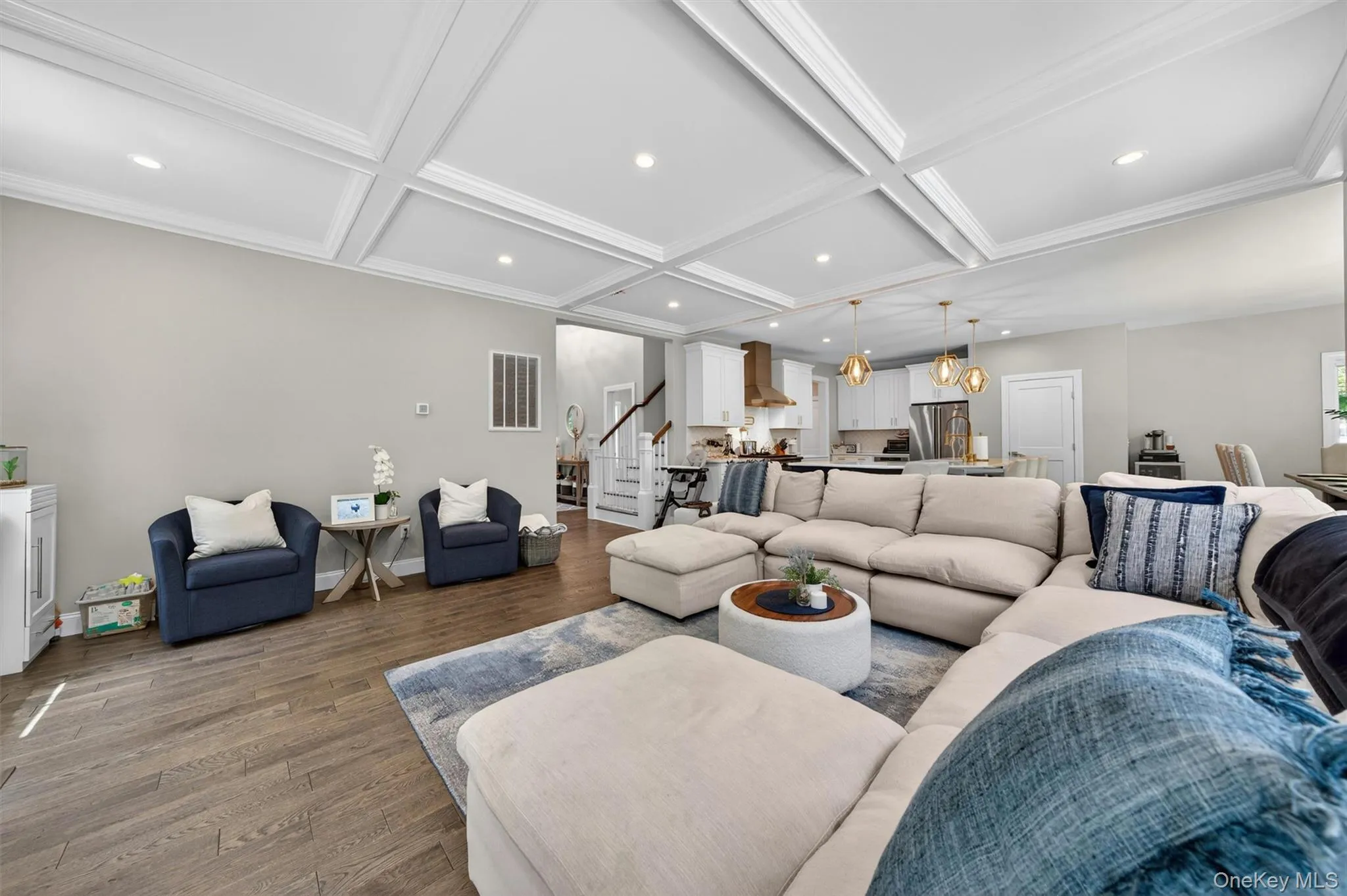 Open-concept living area featuring wood-finish flooring, recessed lighting, and a coffered ceiling Open-concept living area featuring wood-finish flooring, recessed lighting, and a coffered ceiling
