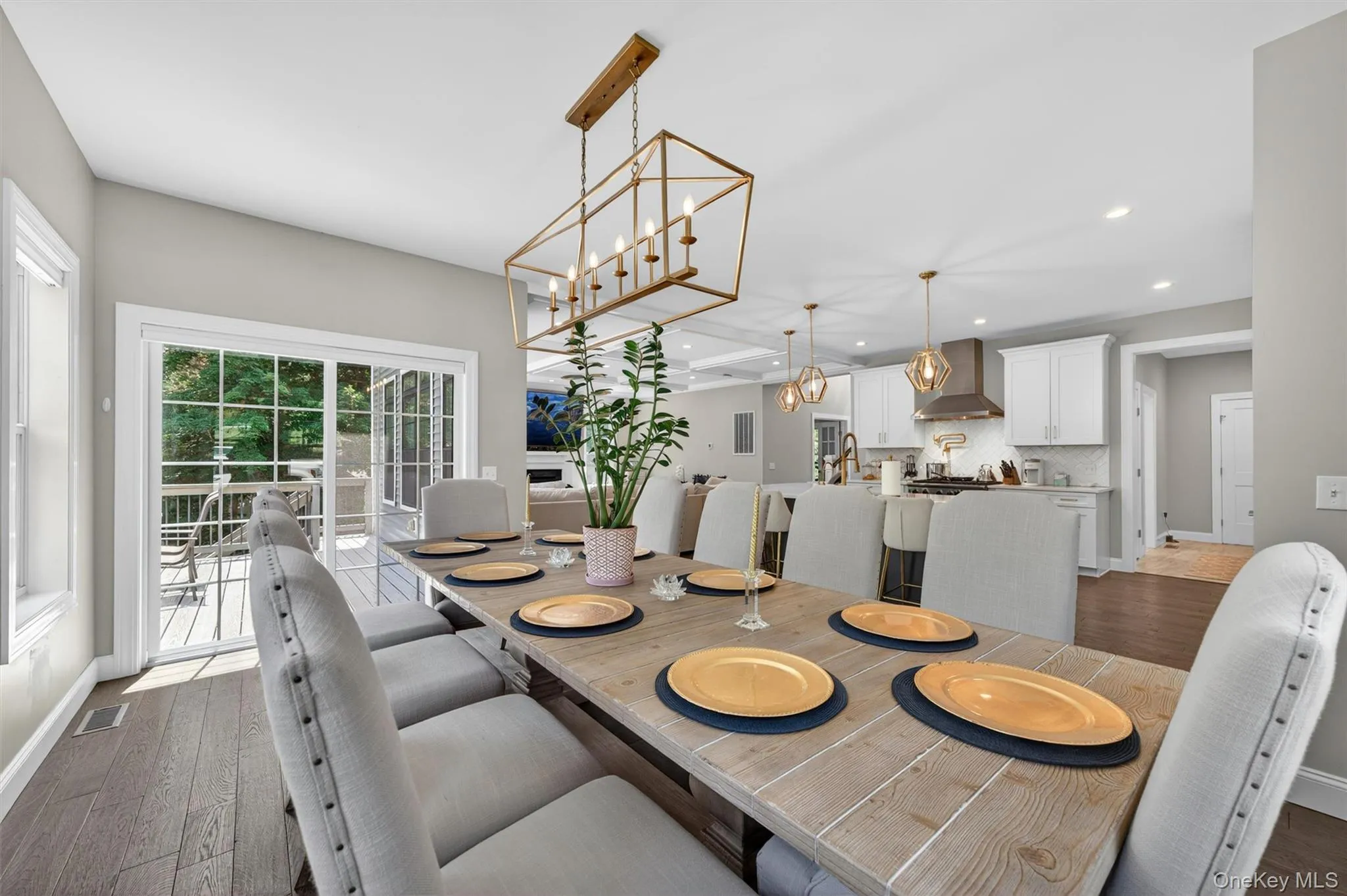Open-concept dining area featuring wood-finish flooring, a contemporary chandelier, and direct access to an outdoor deck through sliding glass doors Open-concept dining area featuring wood-finish flooring, a contemporary chandelier, and direct access to an outdoor deck through sliding glass doors