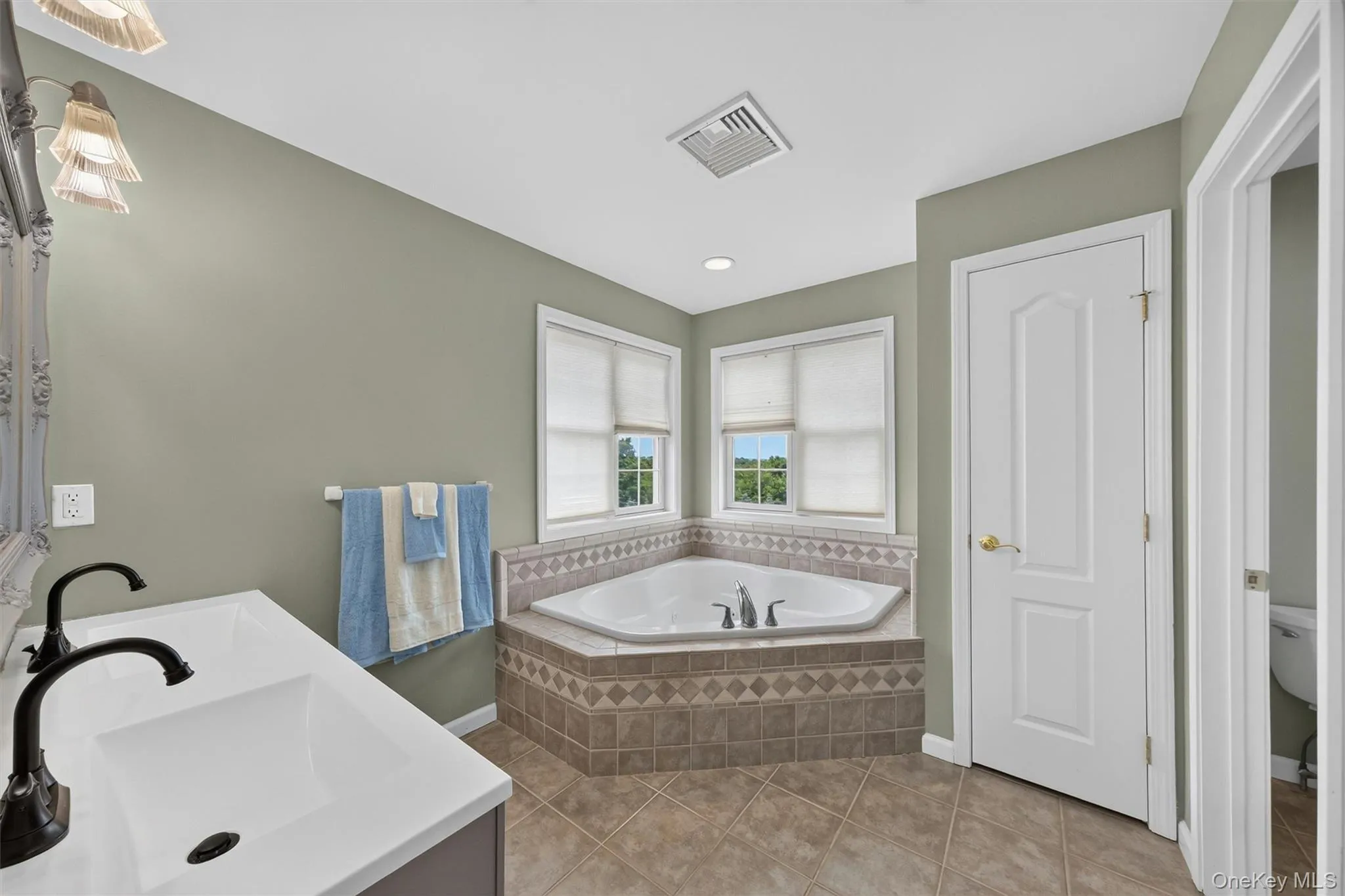 Primary bathroom boasts a Jacuzzi tub with lots of windows, linen closet, double vanity and tiled shower Primary bathroom boasts a Jacuzzi tub with lots of windows, linen closet, double vanity and tiled shower
