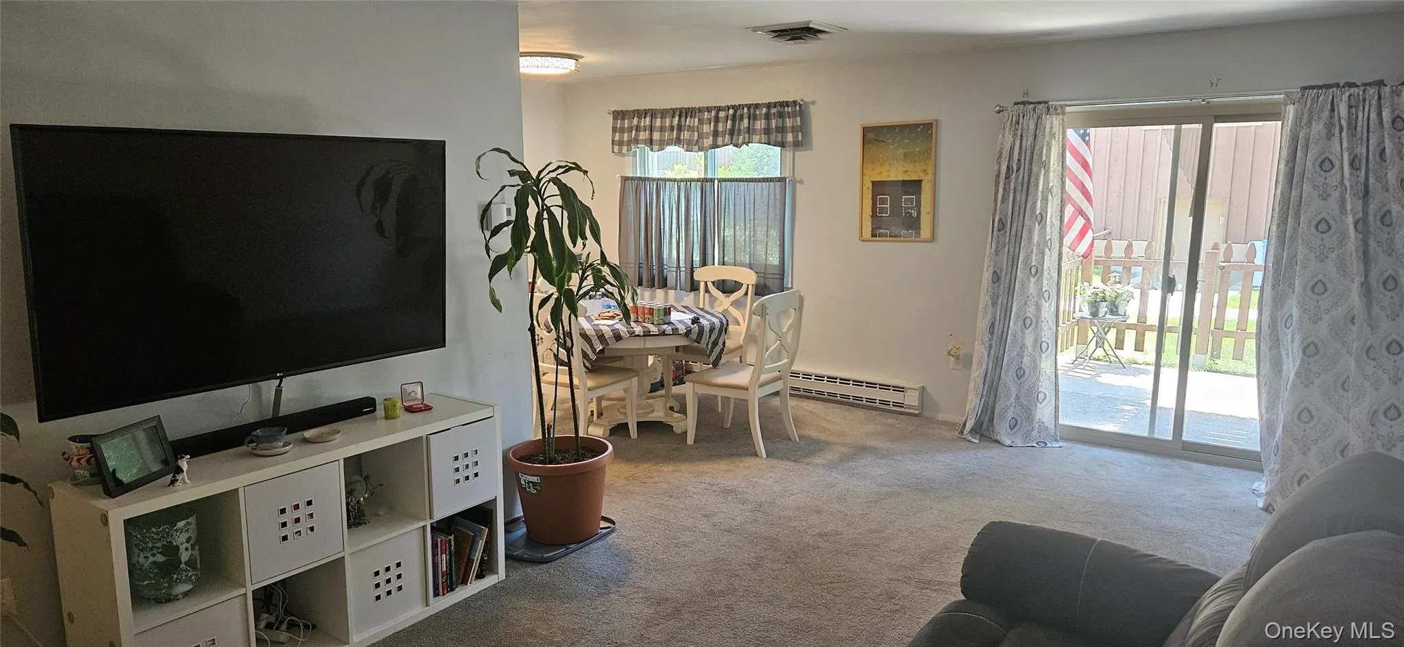 Living area featuring neutral-toned carpeting, a built-in wall partition, and a sliding glass door providing access to an exterior patio Living area featuring neutral-toned carpeting, a built-in wall partition, and a sliding glass door providing access to an exterior patio