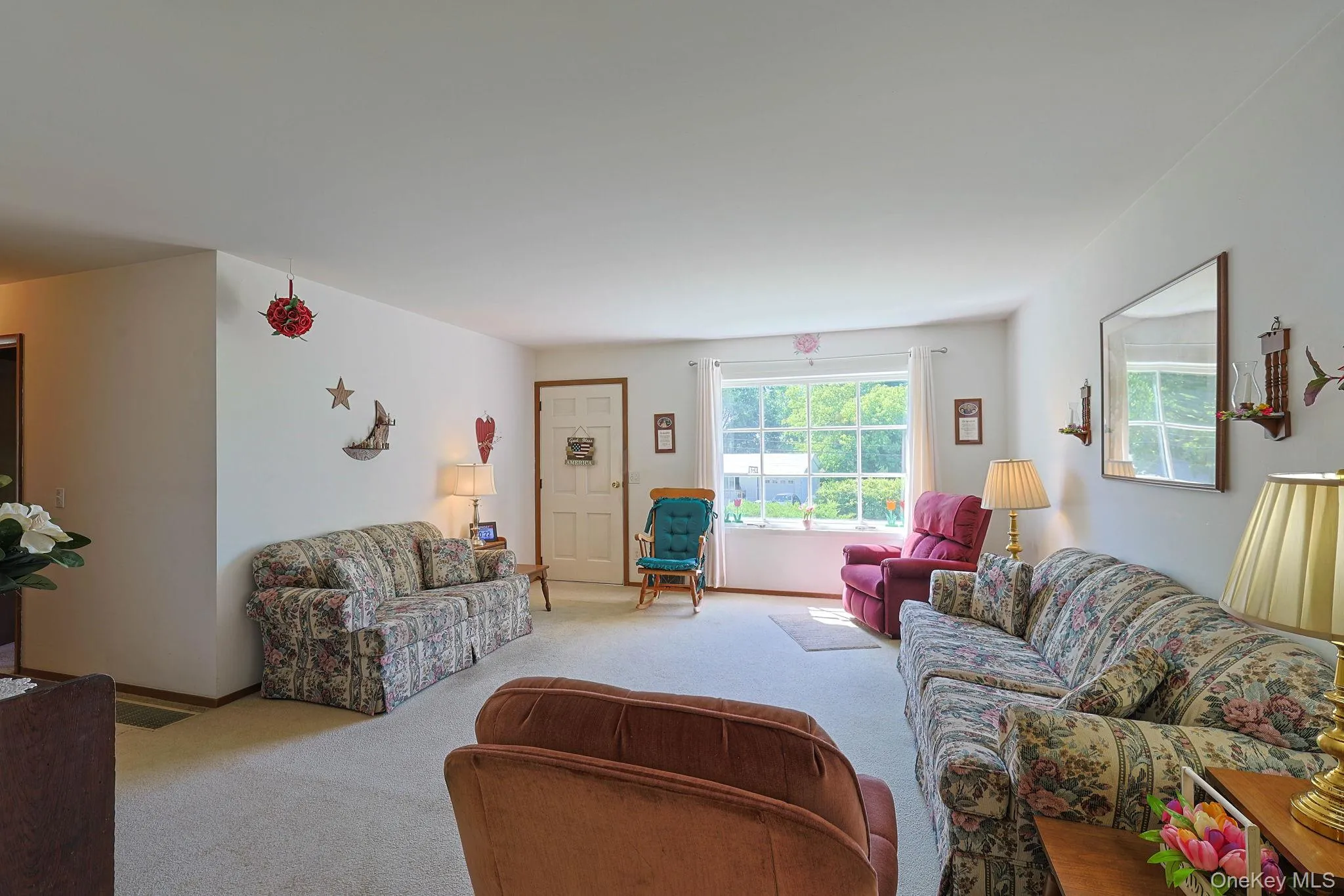 Spacious living room featuring light-colored carpeting and streaming sunlight from the front picture window. Spacious living room featuring light-colored carpeting and streaming sunlight from the front picture window.