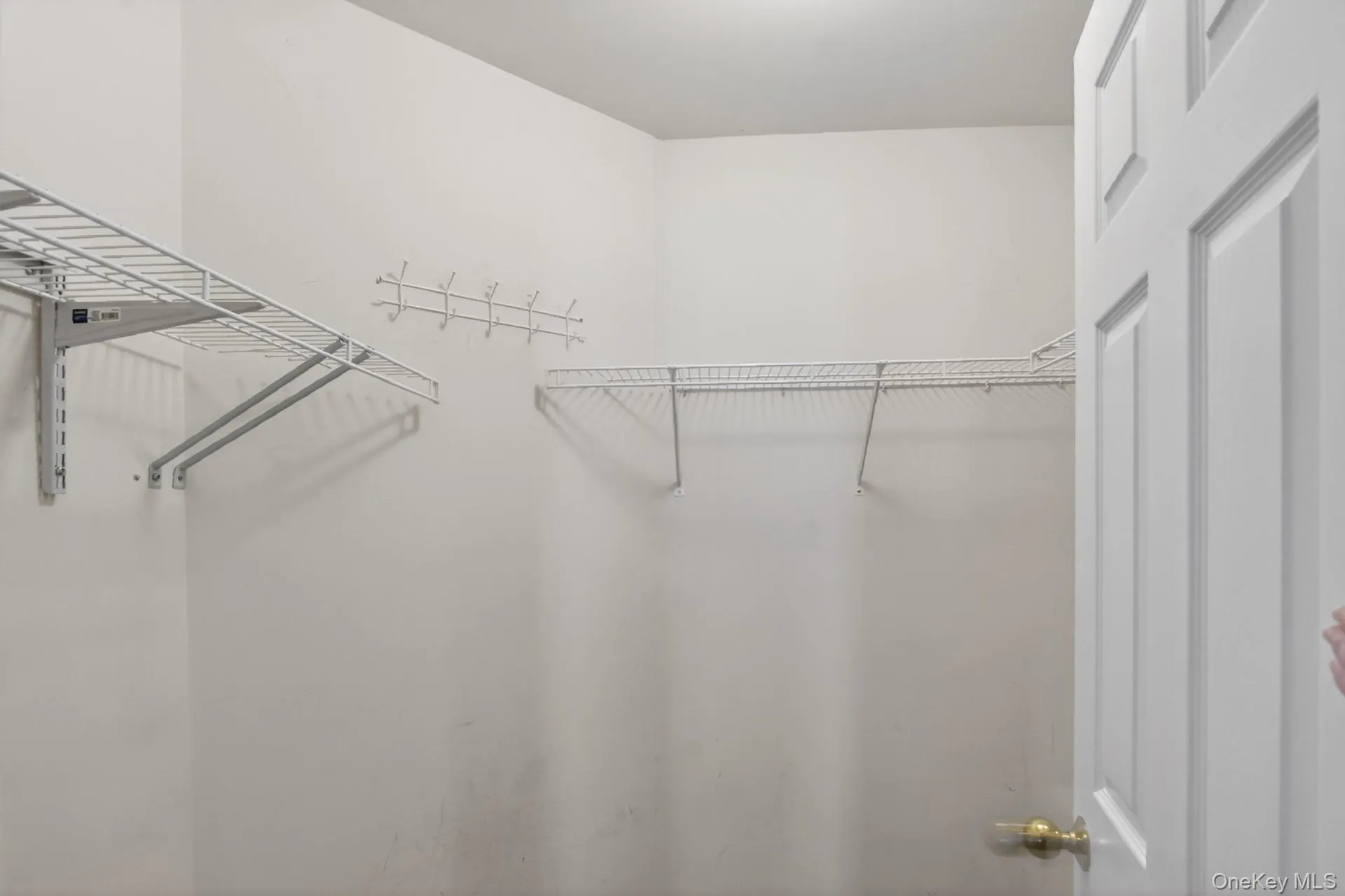 Interior closet space featuring wire shelving systems and a coat rack Interior closet space featuring wire shelving systems and a coat rack