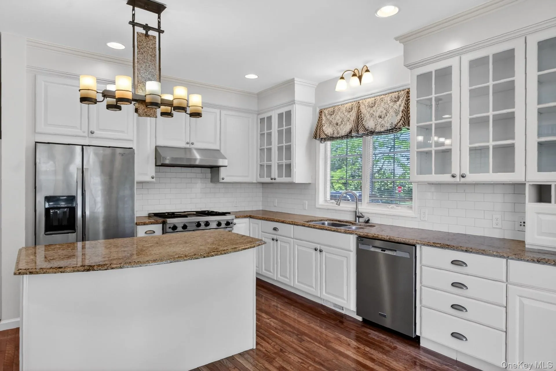 Kitchen featuring white cabinetry, wood-finish flooring, and granite countertops Kitchen featuring white cabinetry, wood-finish flooring, and granite countertops