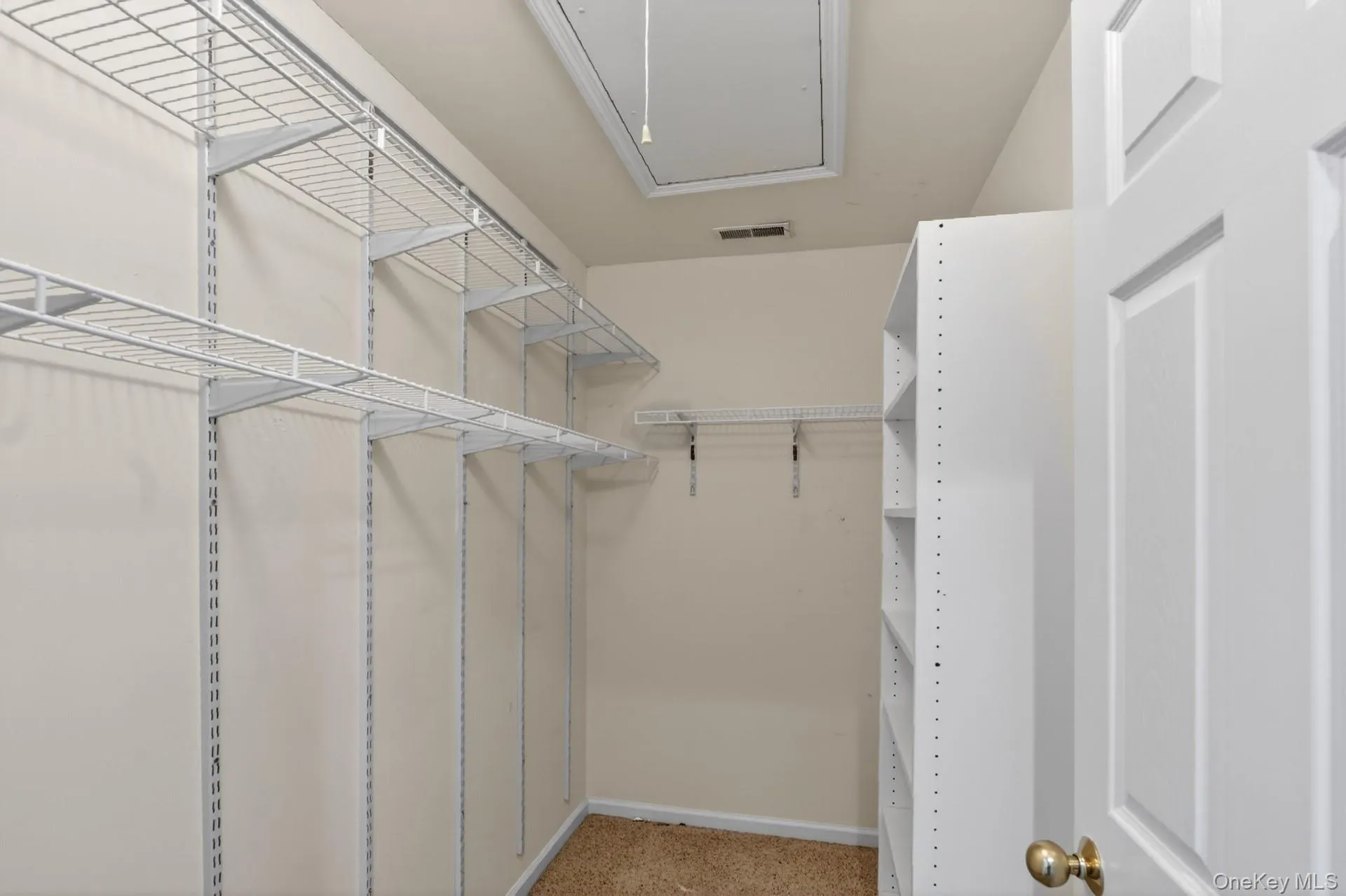 Walk-in closet featuring wire shelving, built-in cubby shelving, and neutral carpeting Walk-in closet featuring wire shelving, built-in cubby shelving, and neutral carpeting