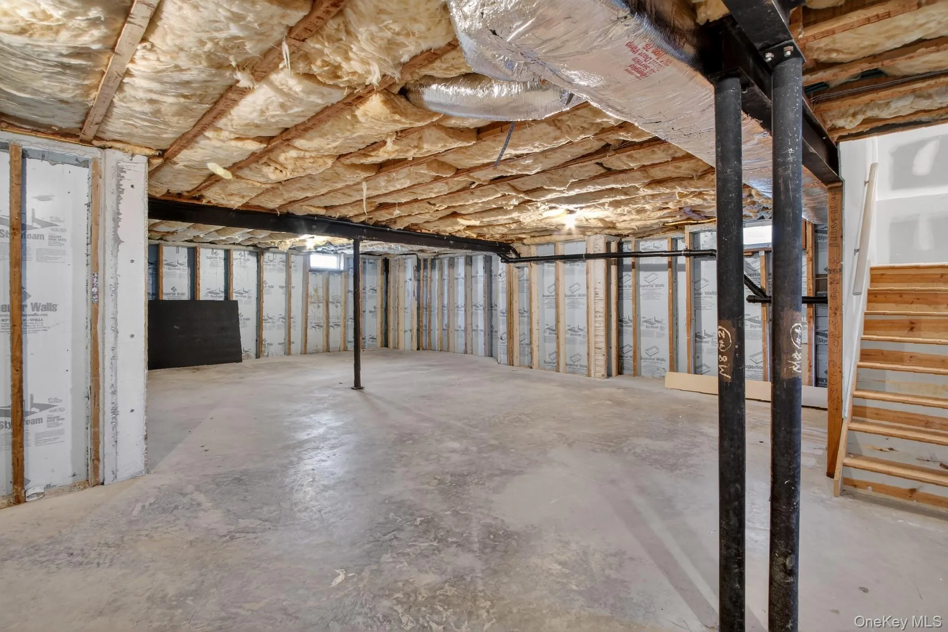 Unfinished basement featuring a concrete floor, exposed insulation, structural support beams, and visible framing Unfinished basement featuring a concrete floor, exposed insulation, structural support beams, and visible framing