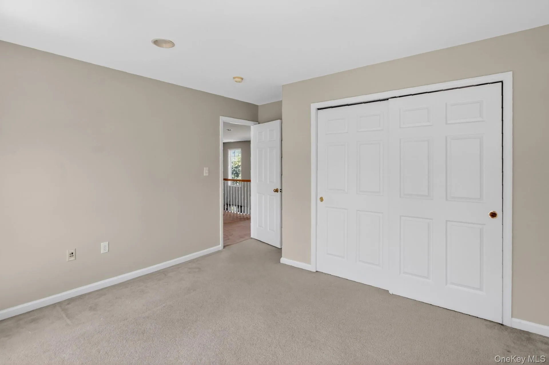 Carpeted room featuring a white bi-fold closet, neutral wall paint, white baseboards, and recessed lighting Carpeted room featuring a white bi-fold closet, neutral wall paint, white baseboards, and recessed lighting