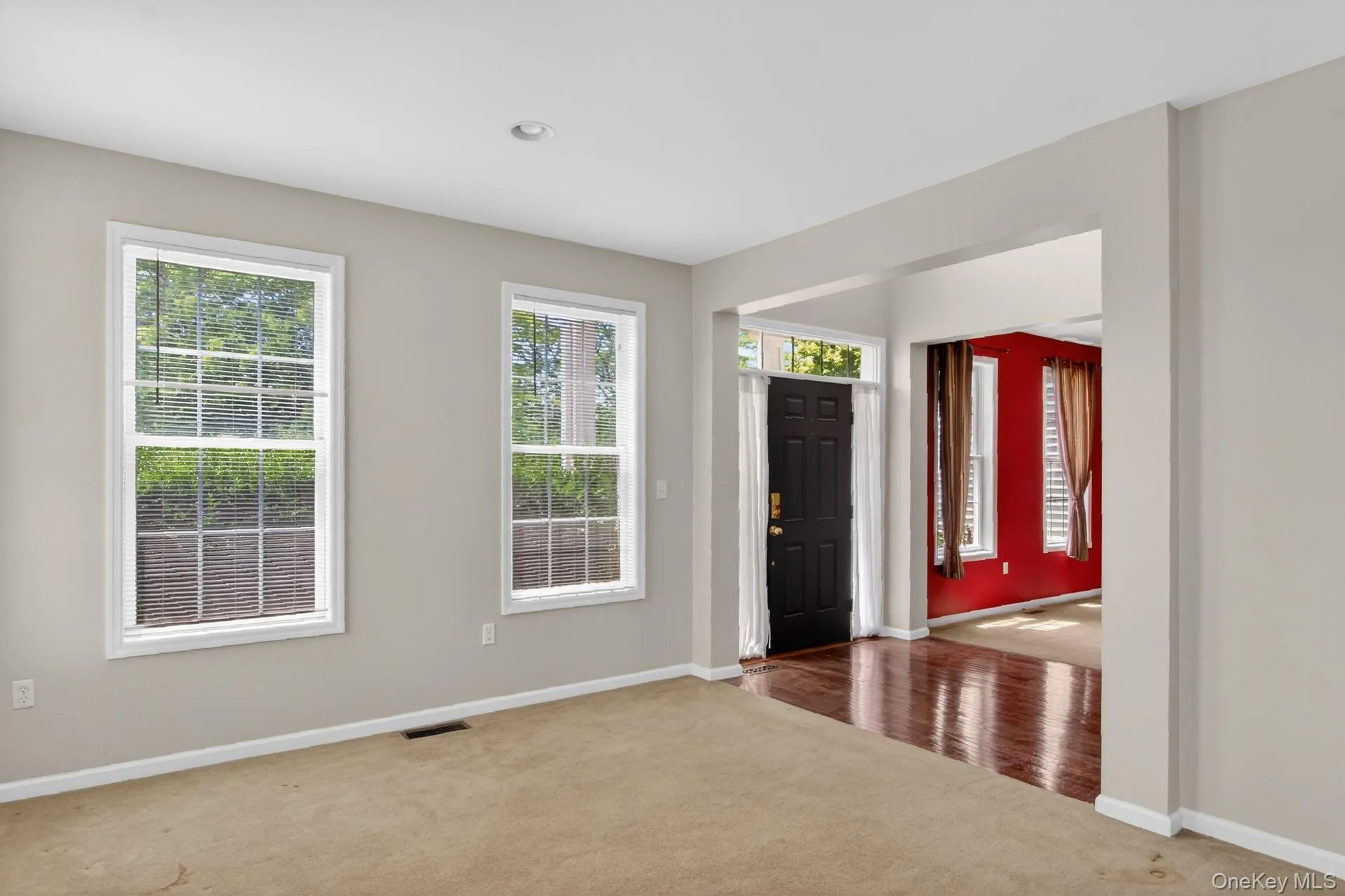 Carpeted main living area with two large windows Carpeted main living area with two large windows