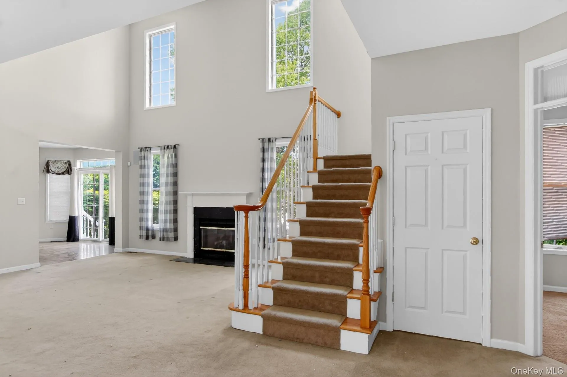 Two-story foyer with a carpeted staircase featuring a wood handrail and white spindles Two-story foyer with a carpeted staircase featuring a wood handrail and white spindles