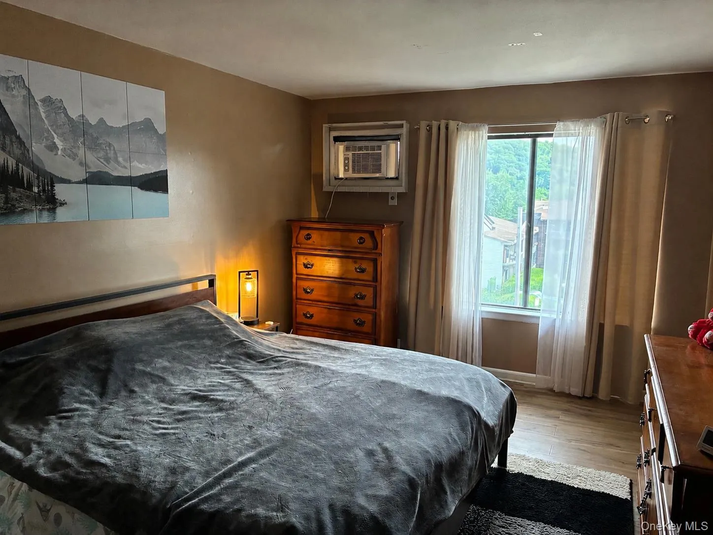Bedroom featuring wood-finish flooring, a window air conditioning unit, and a window with natural light Bedroom featuring wood-finish flooring, a window air conditioning unit, and a window with natural light