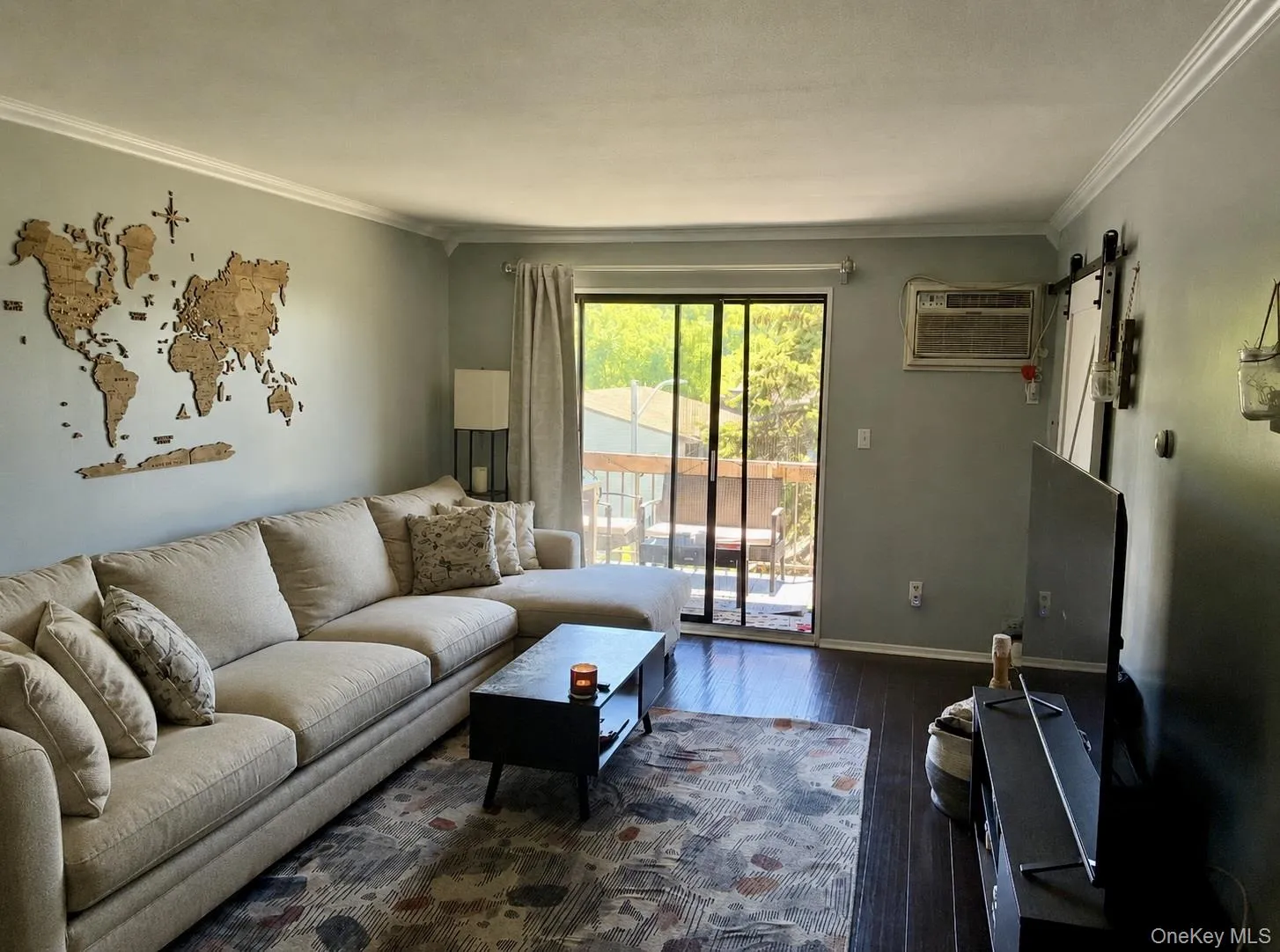 Living area featuring dark wood-finish flooring, light grey walls, and white crown molding Living area featuring dark wood-finish flooring, light grey walls, and white crown molding
