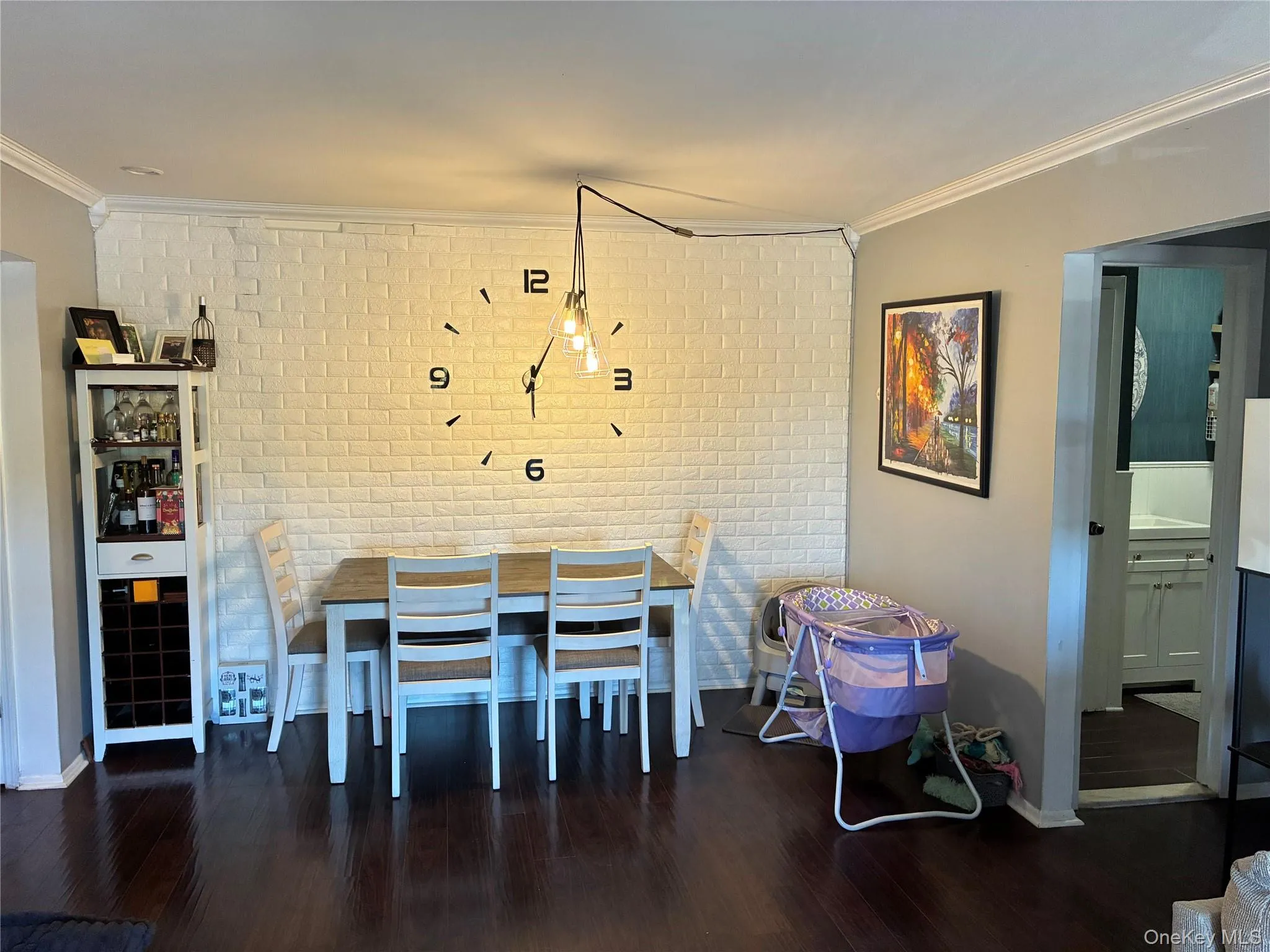 Dining area featuring an accent wall with white brick-style paneling, dark wood-finish flooring, and crown molding Dining area featuring an accent wall with white brick-style paneling, dark wood-finish flooring, and crown molding