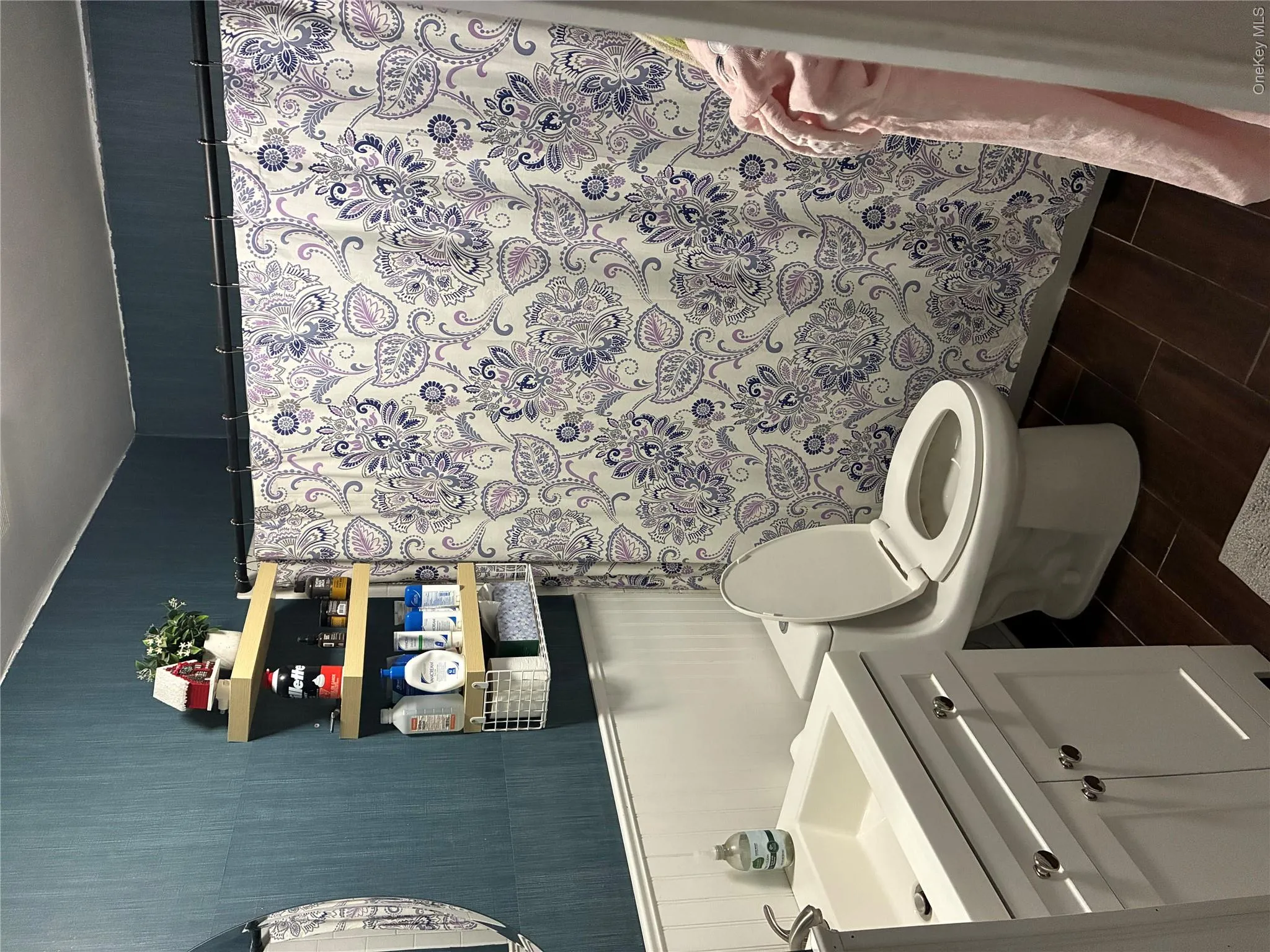 Bathroom featuring dark wood-finish flooring, white wainscoting, and blue accent wall Bathroom featuring dark wood-finish flooring, white wainscoting, and blue accent wall