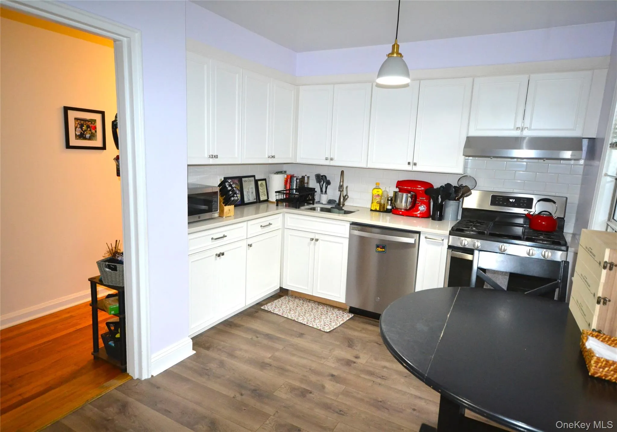 Kitchen featuring appliances with stainless steel finishes, under cabinet range hood, and tiled backsplash Kitchen featuring appliances with stainless steel finishes, under cabinet range hood, and tiled backsplash