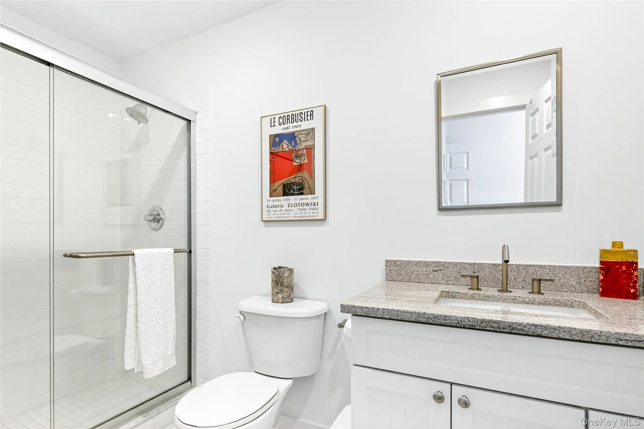 Bathroom featuring a walk-in shower with clear glass enclosure, a white subway tile surround, and a vanity with a light-colored countertop Bathroom featuring a walk-in shower with clear glass enclosure, a white subway tile surround, and a vanity with a light-colored countertop