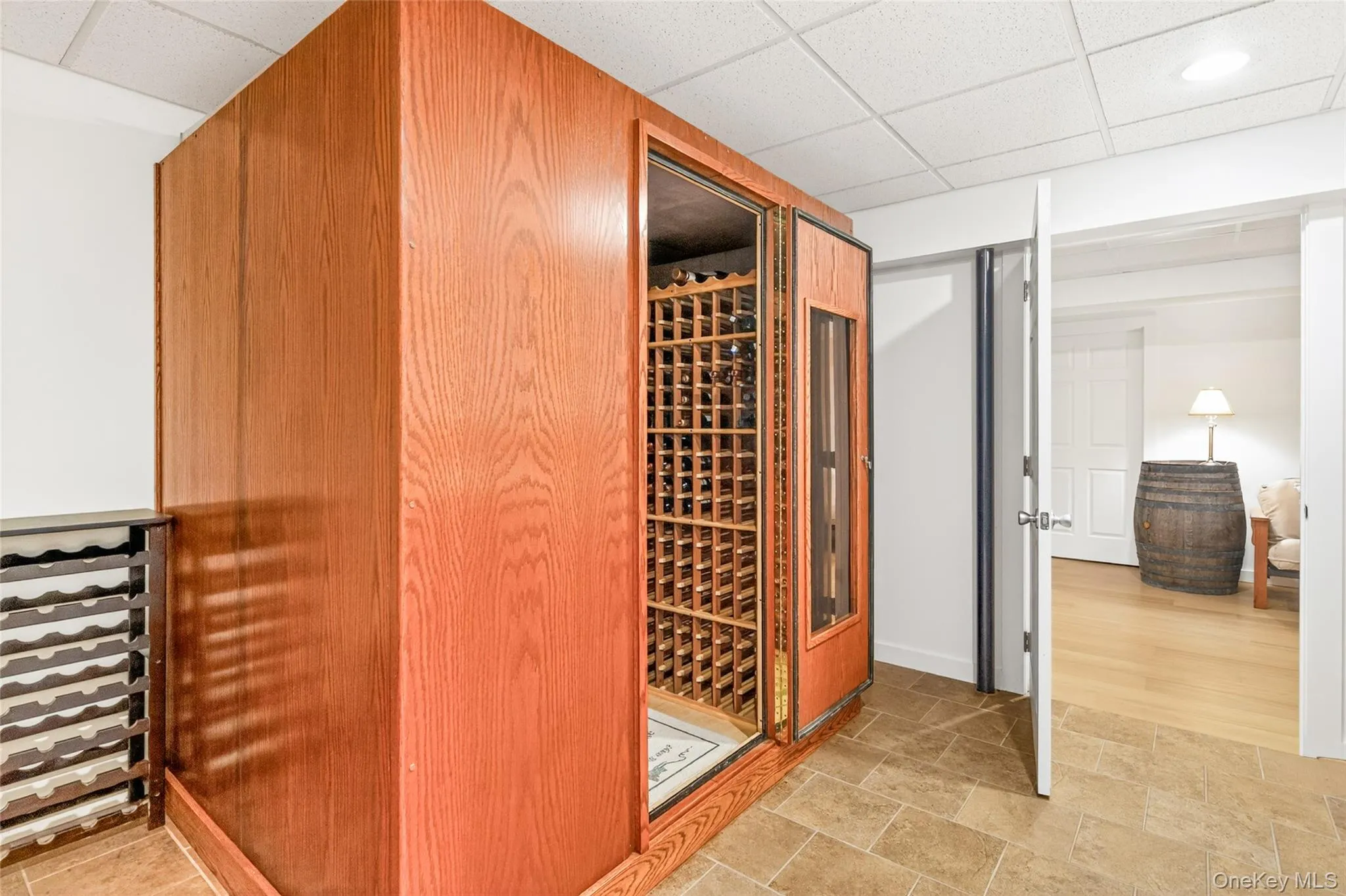 Custom wood-paneled wine cellar featuring glass-front doors, integrated shelving, and a tiled floor Custom wood-paneled wine cellar featuring glass-front doors, integrated shelving, and a tiled floor