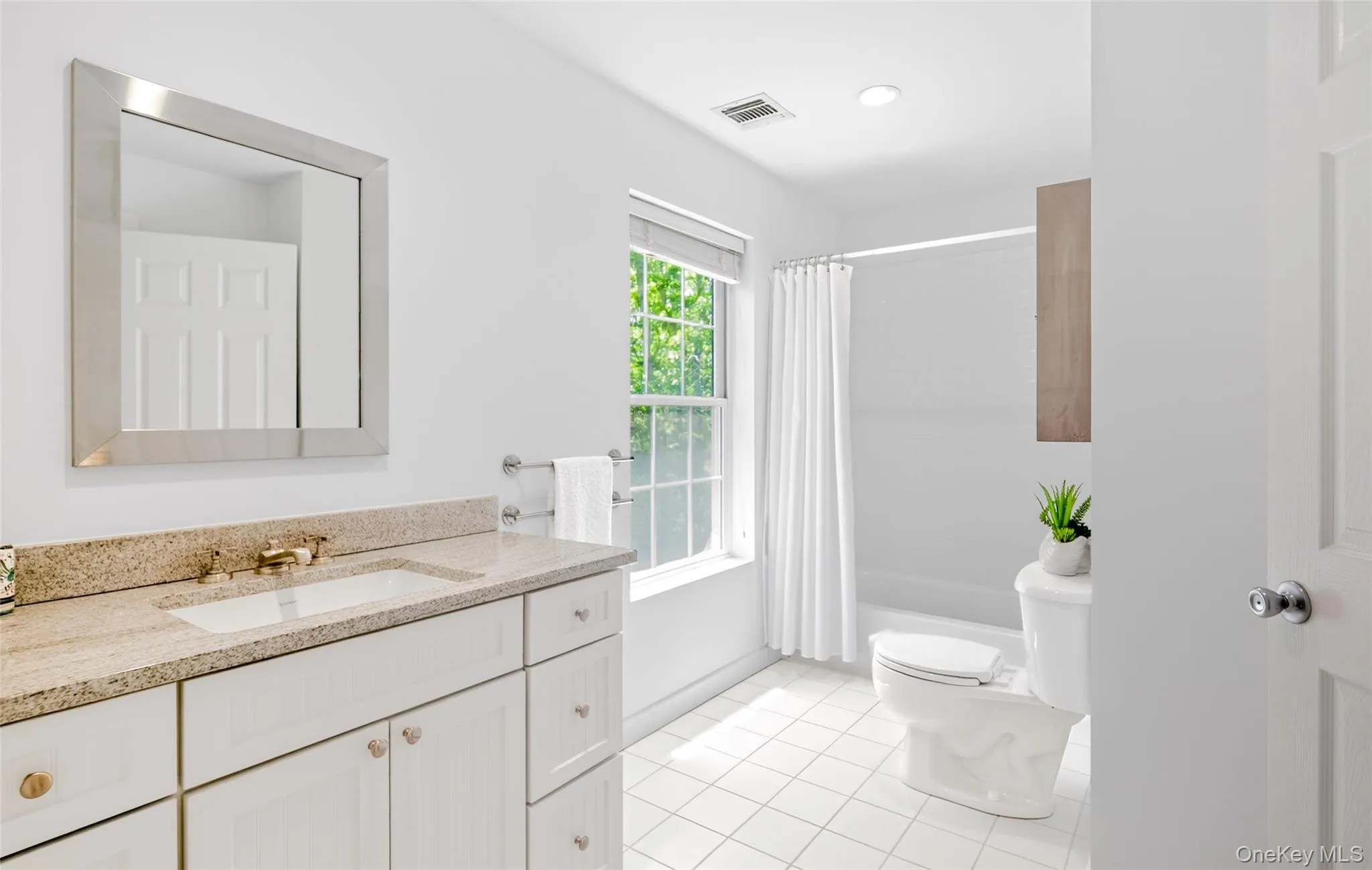 Full bathroom featuring a single vanity with a granite countertop, white cabinetry, undermount sink, and a framed mirror Full bathroom featuring a single vanity with a granite countertop, white cabinetry, undermount sink, and a framed mirror