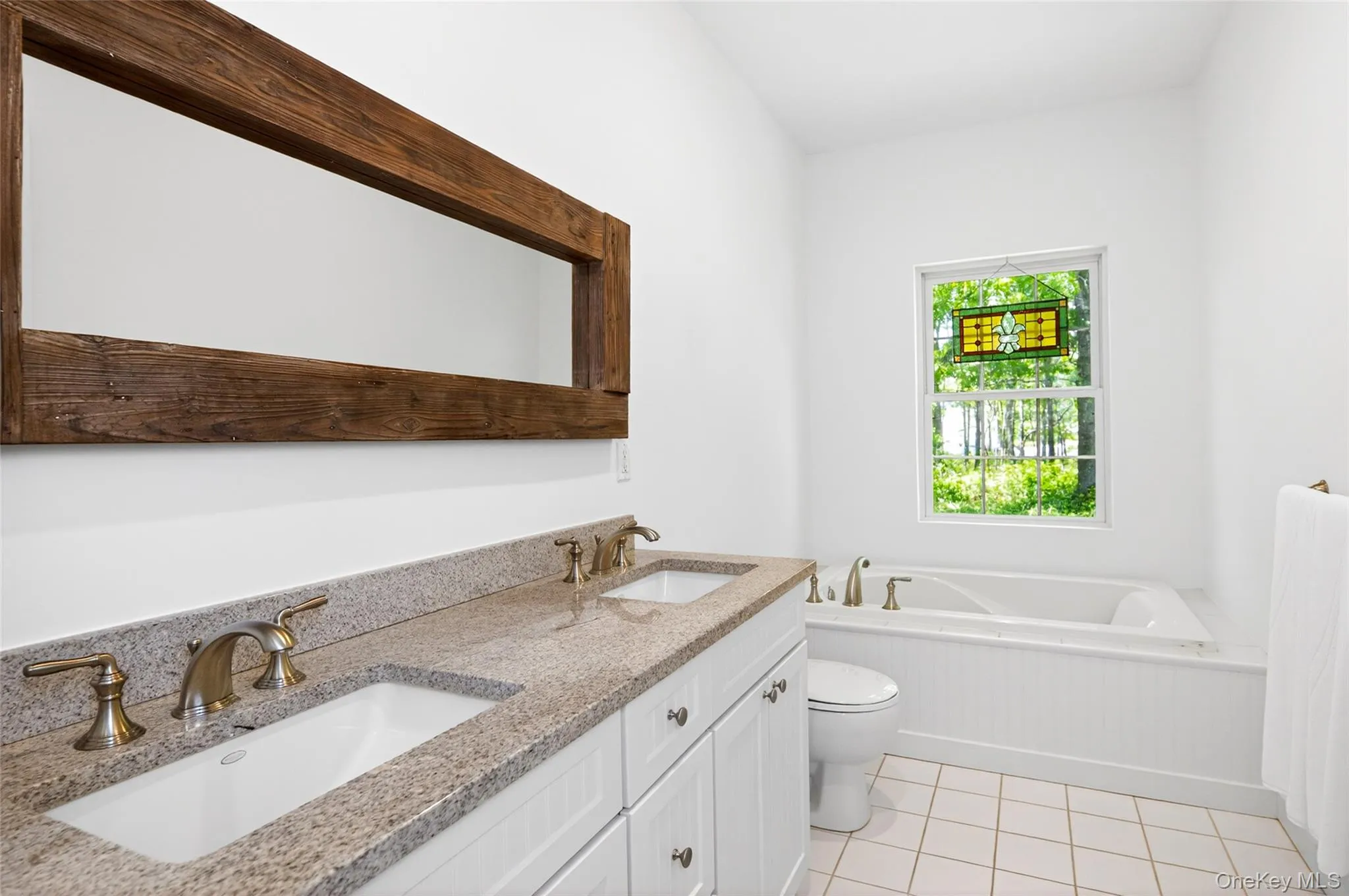 Spacious bathroom featuring a double vanity with granite countertops, integrated sinks, and bronze-finish fixtures Spacious bathroom featuring a double vanity with granite countertops, integrated sinks, and bronze-finish fixtures