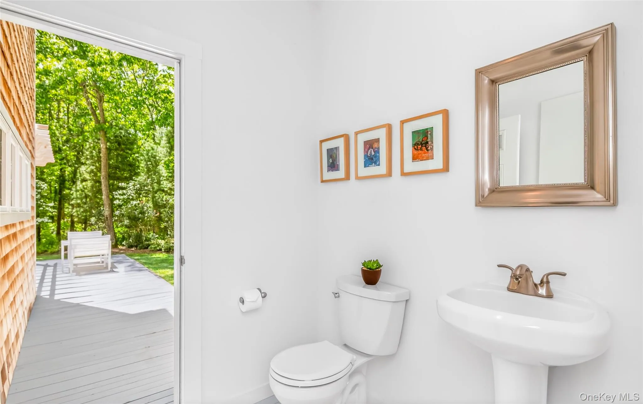 Powder Room Bathroom featuring a pedestal sink, framed mirror, and toilet and access t0the pool area Powder Room Bathroom featuring a pedestal sink, framed mirror, and toilet and access t0the pool area