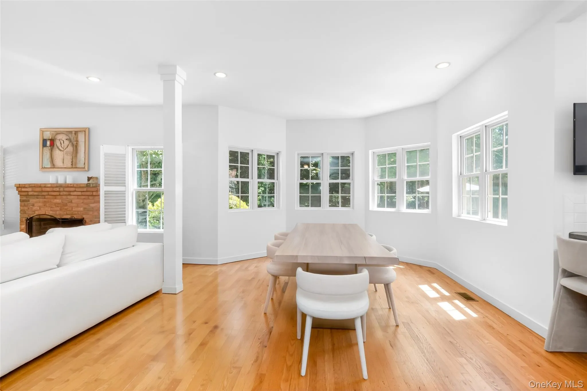 Bright dining area featuring hardwood flooring, multiple large windows, recessed lighting, and white walls Bright dining area featuring hardwood flooring, multiple large windows, recessed lighting, and white walls