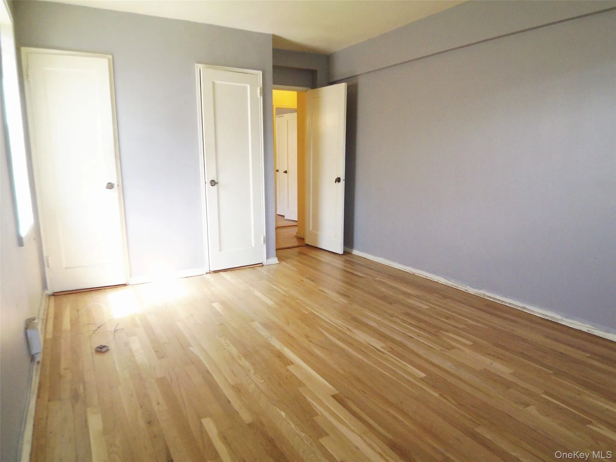 Hardwood flooring with a natural finish, light grey walls, and white trim Hardwood flooring with a natural finish, light grey walls, and white trim