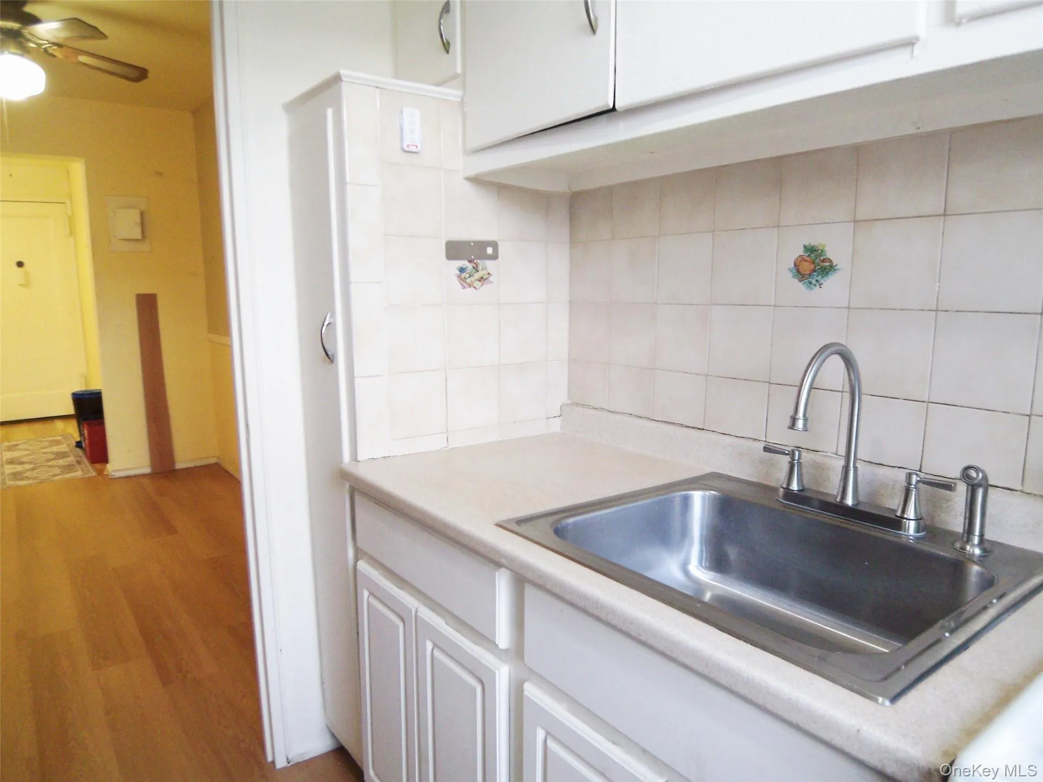 Kitchenette featuring a stainless steel sink, gooseneck faucet, light-toned countertop, and tiled backsplash Kitchenette featuring a stainless steel sink, gooseneck faucet, light-toned countertop, and tiled backsplash