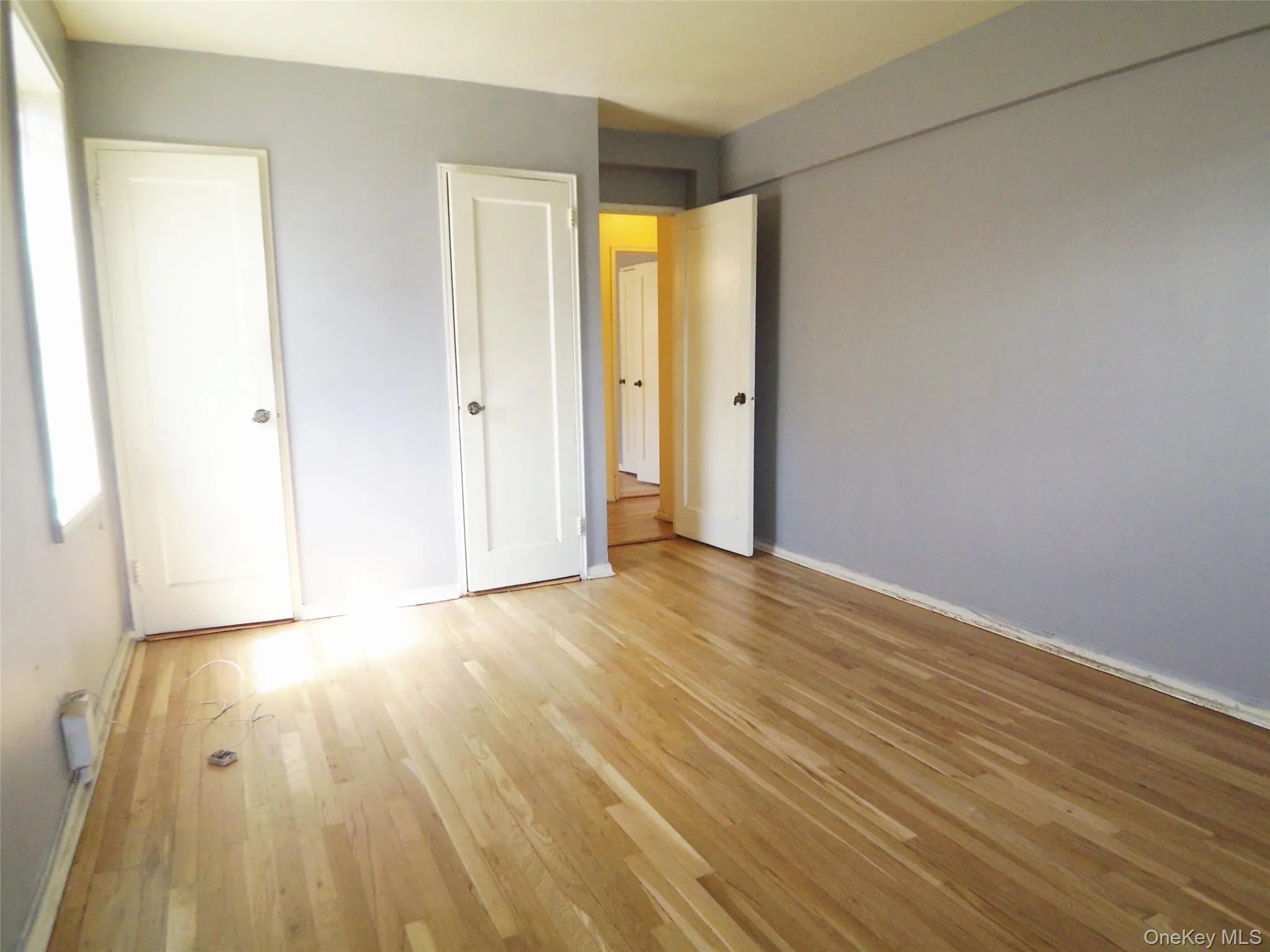 Hardwood flooring throughout, featuring light gray walls, white trim, and white paneled doors Hardwood flooring throughout, featuring light gray walls, white trim, and white paneled doors